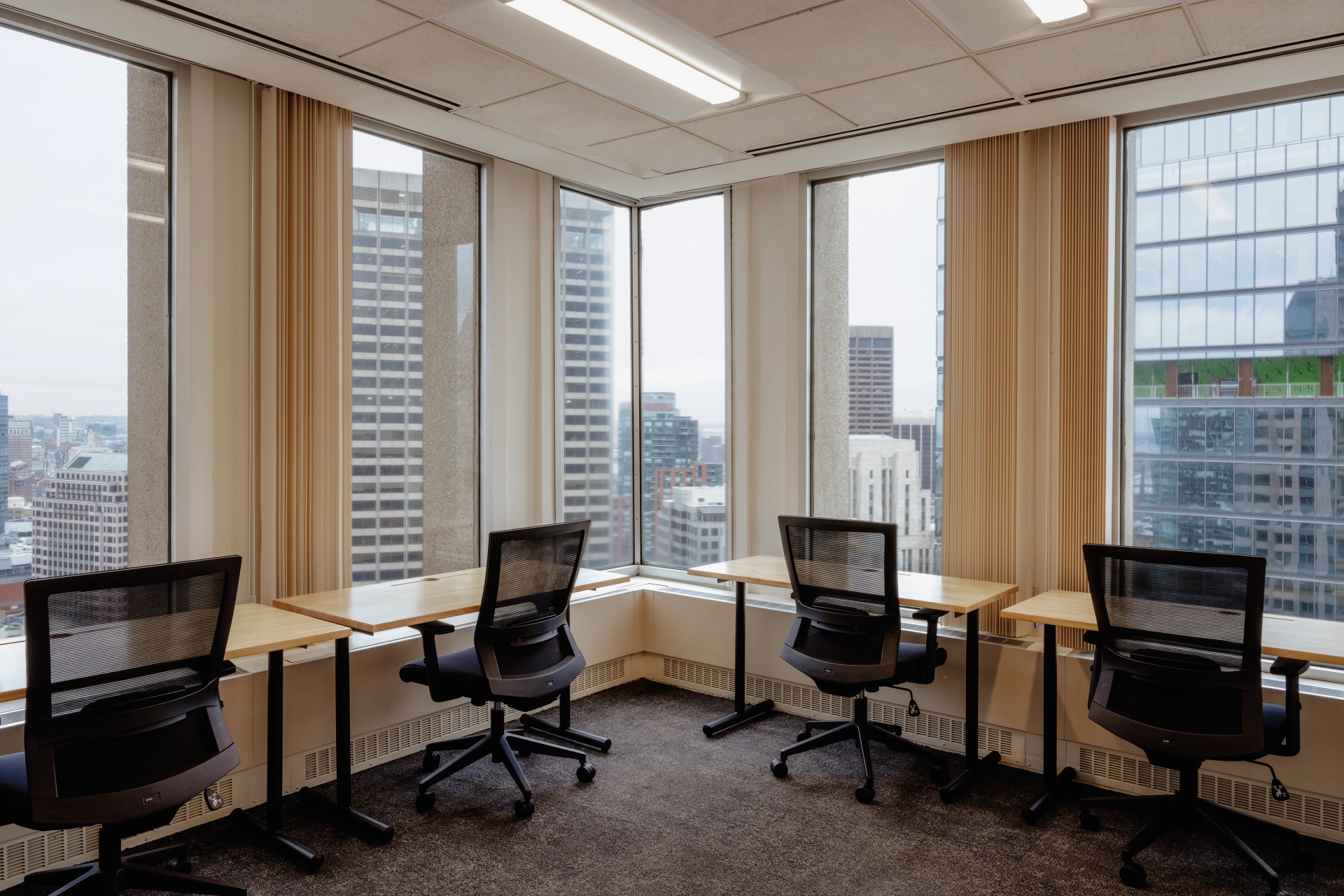 A Boston office meeting room with desks and chairs and a view of the city.