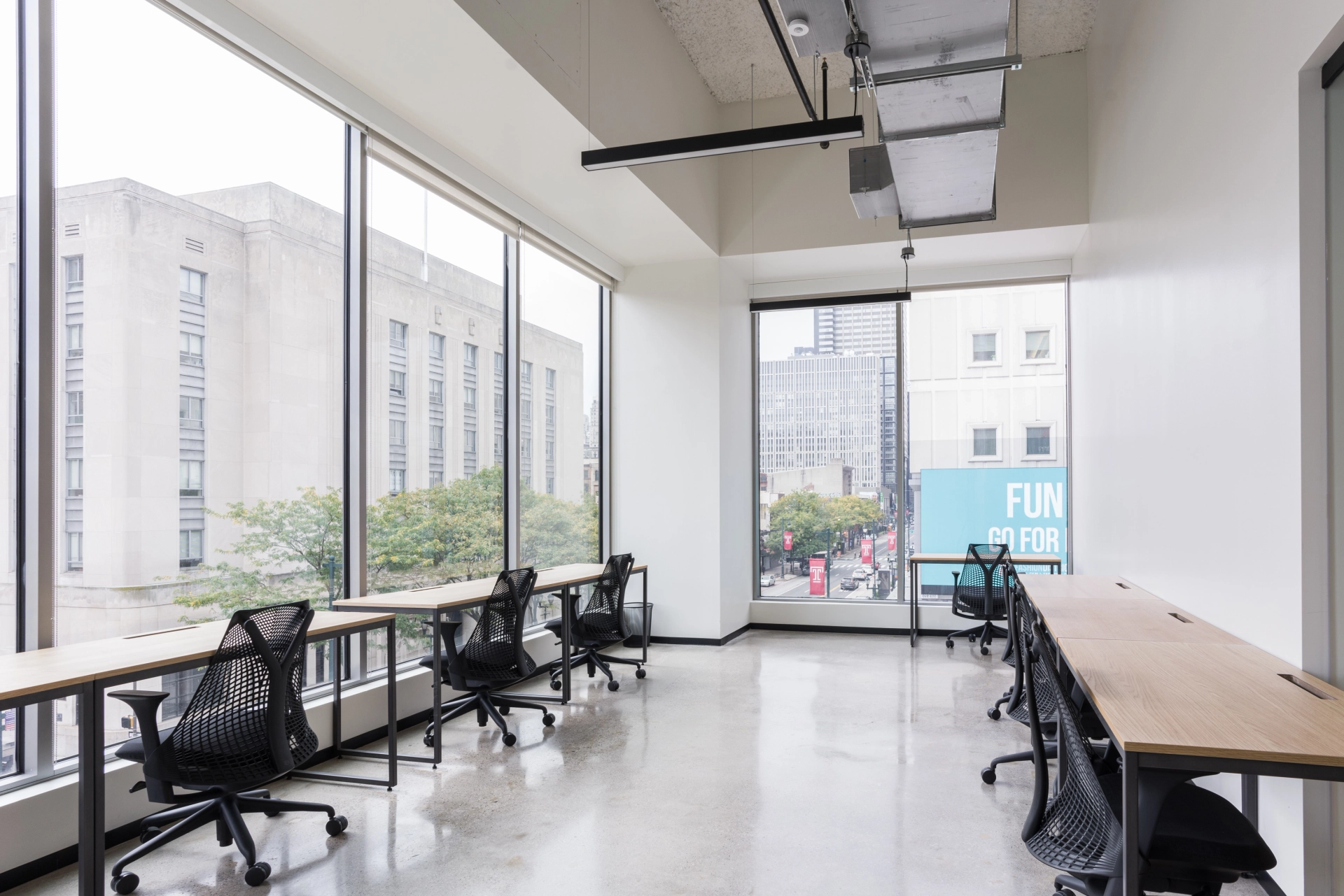 Un espace de coworking avec des bureaux et des chaises devant une grande fenêtre.