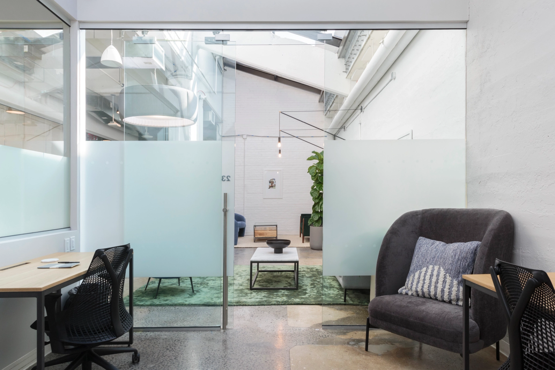 A modern workspace in Brooklyn featuring a glass wall and comfortable chairs.