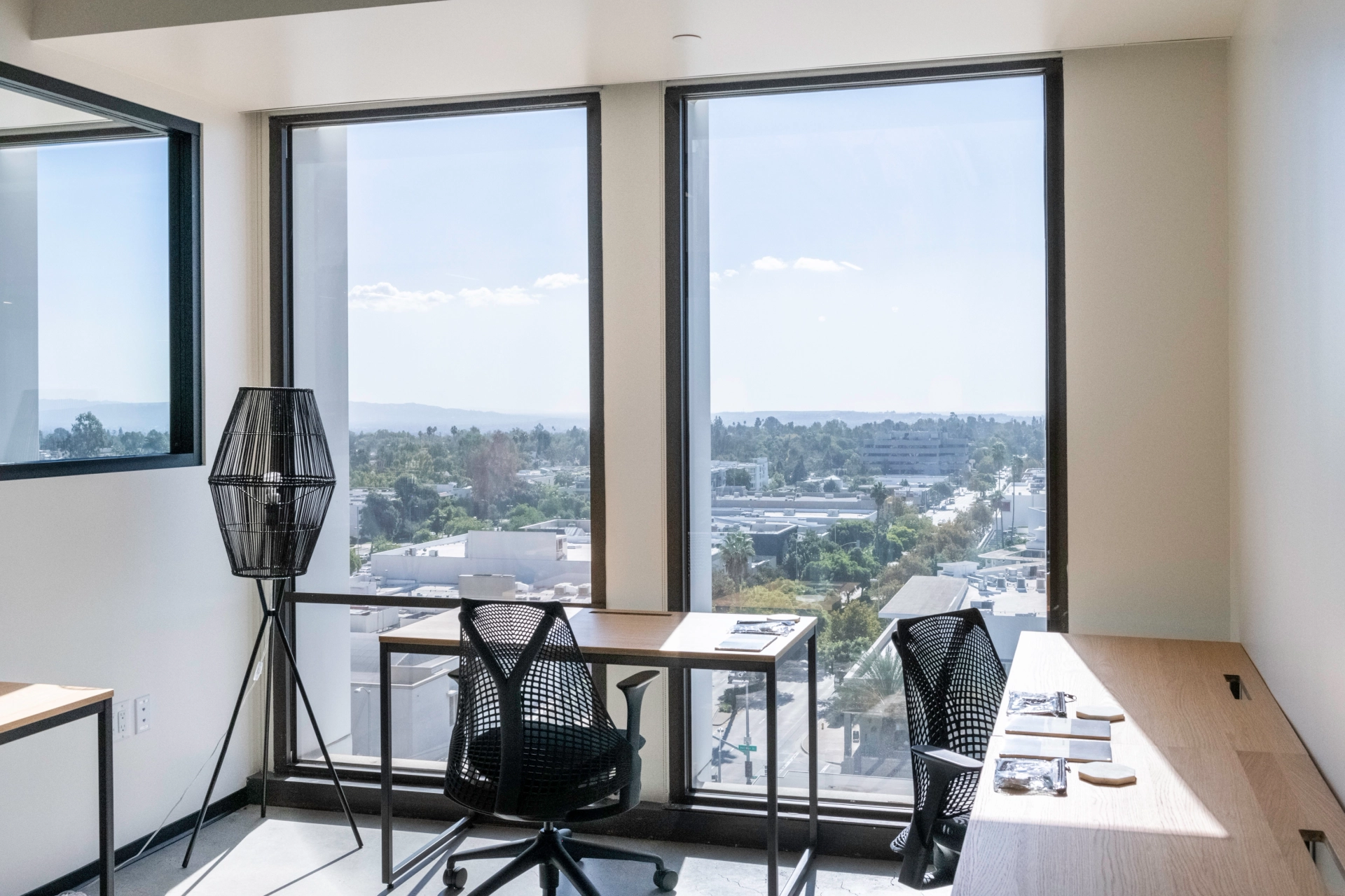 A Pasadena coworking workspace featuring two desks and a window with a city view.