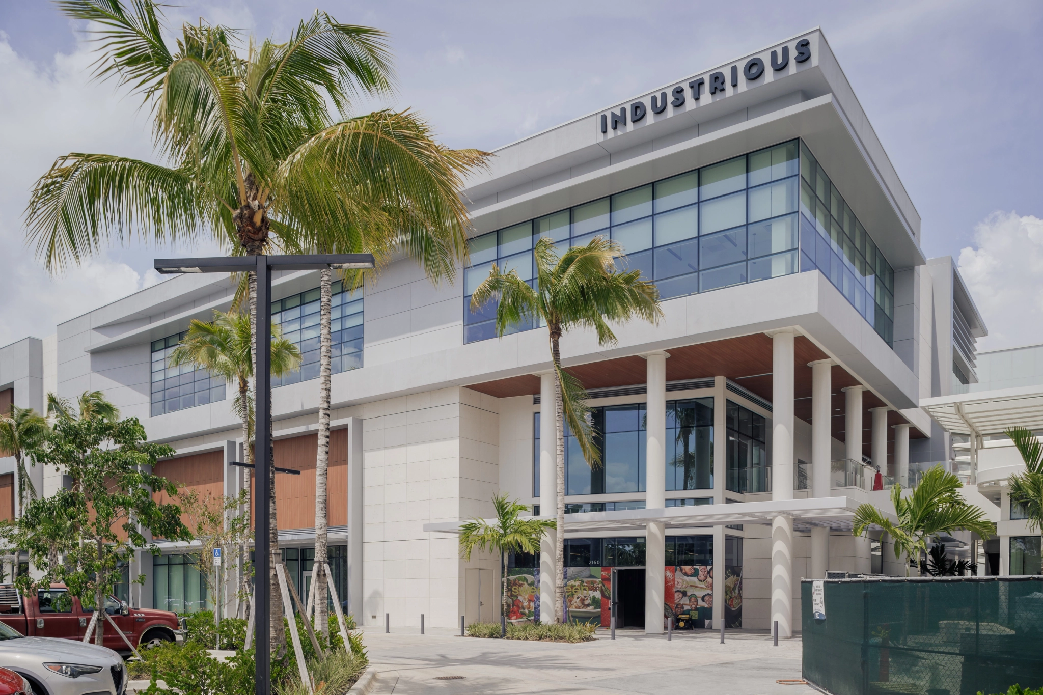 A coworking space with palm trees in front of it.