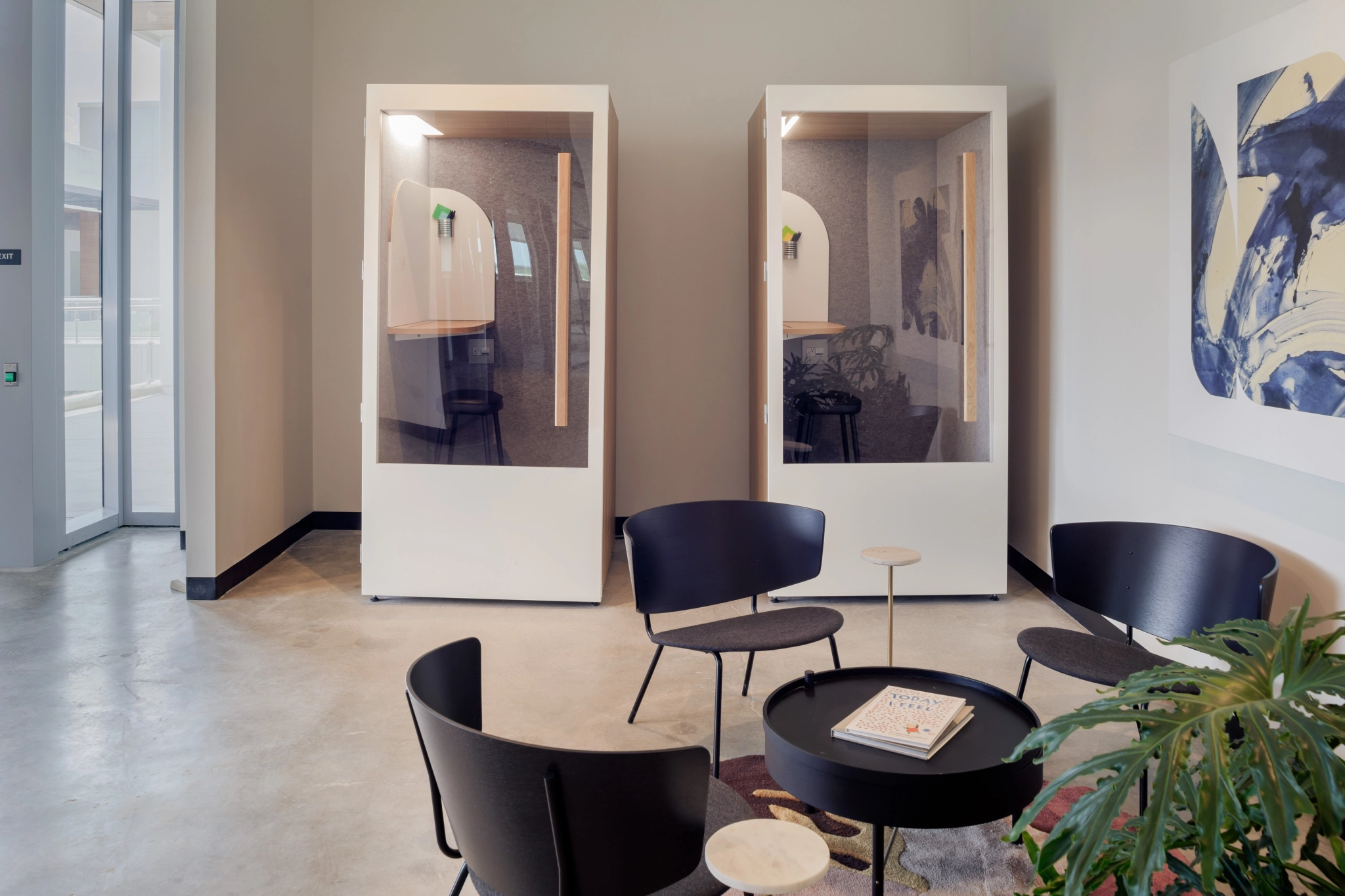 Two black chairs and a plant in an office coworking space.