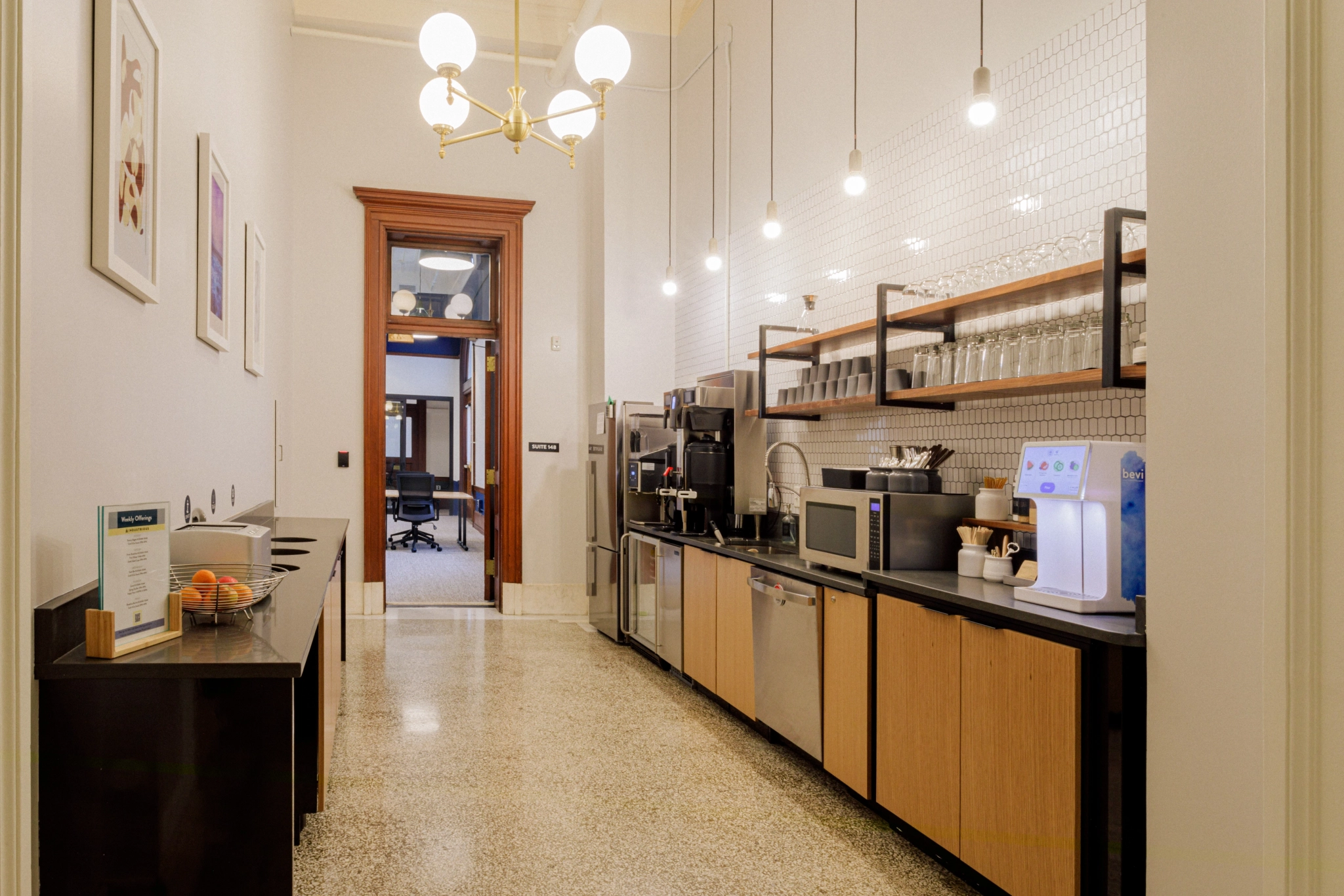 une kitchenette dans une salle de réunion de bureau avec un réfrigérateur et une cafetière.