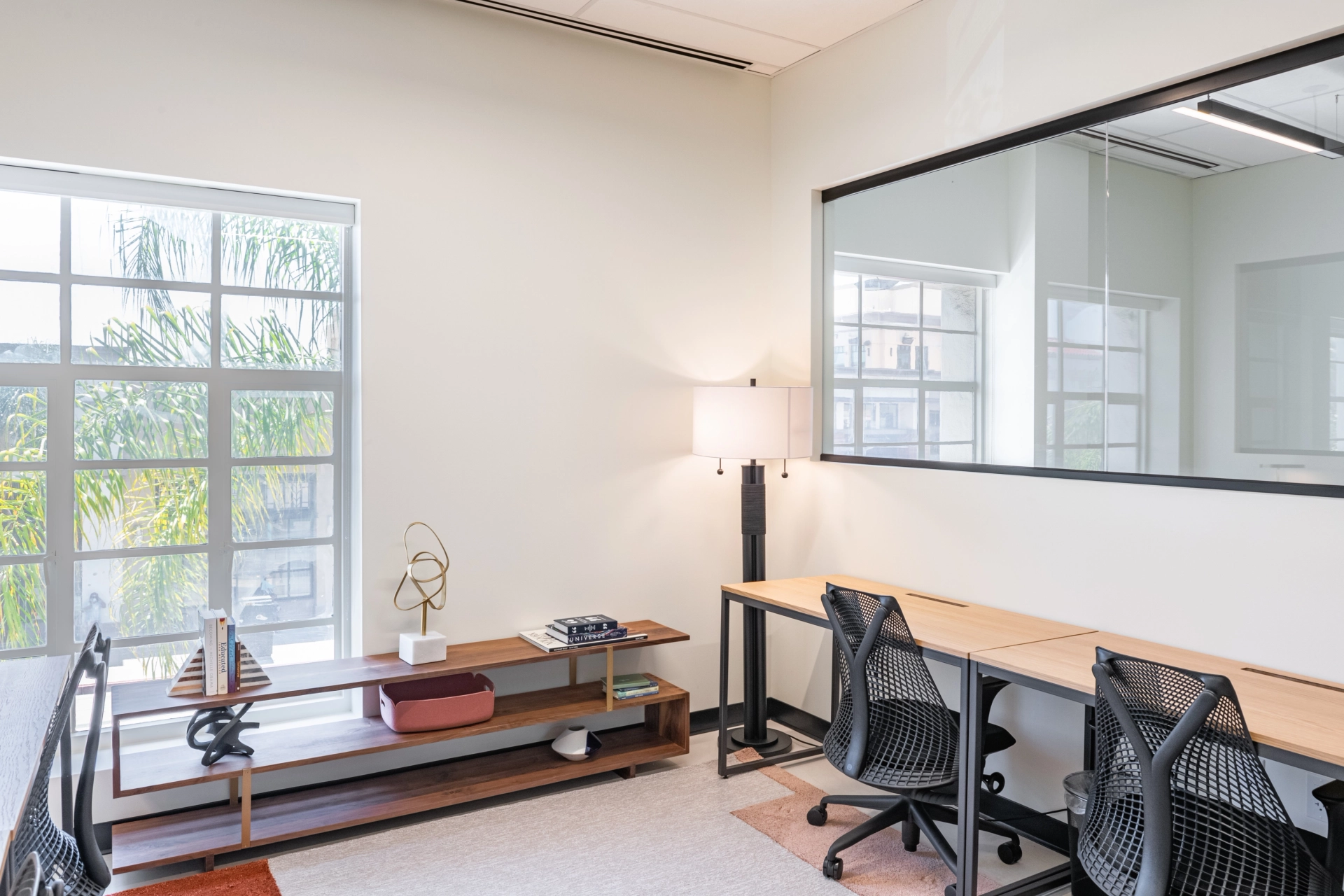 An office workspace with dual desks and a mirror.