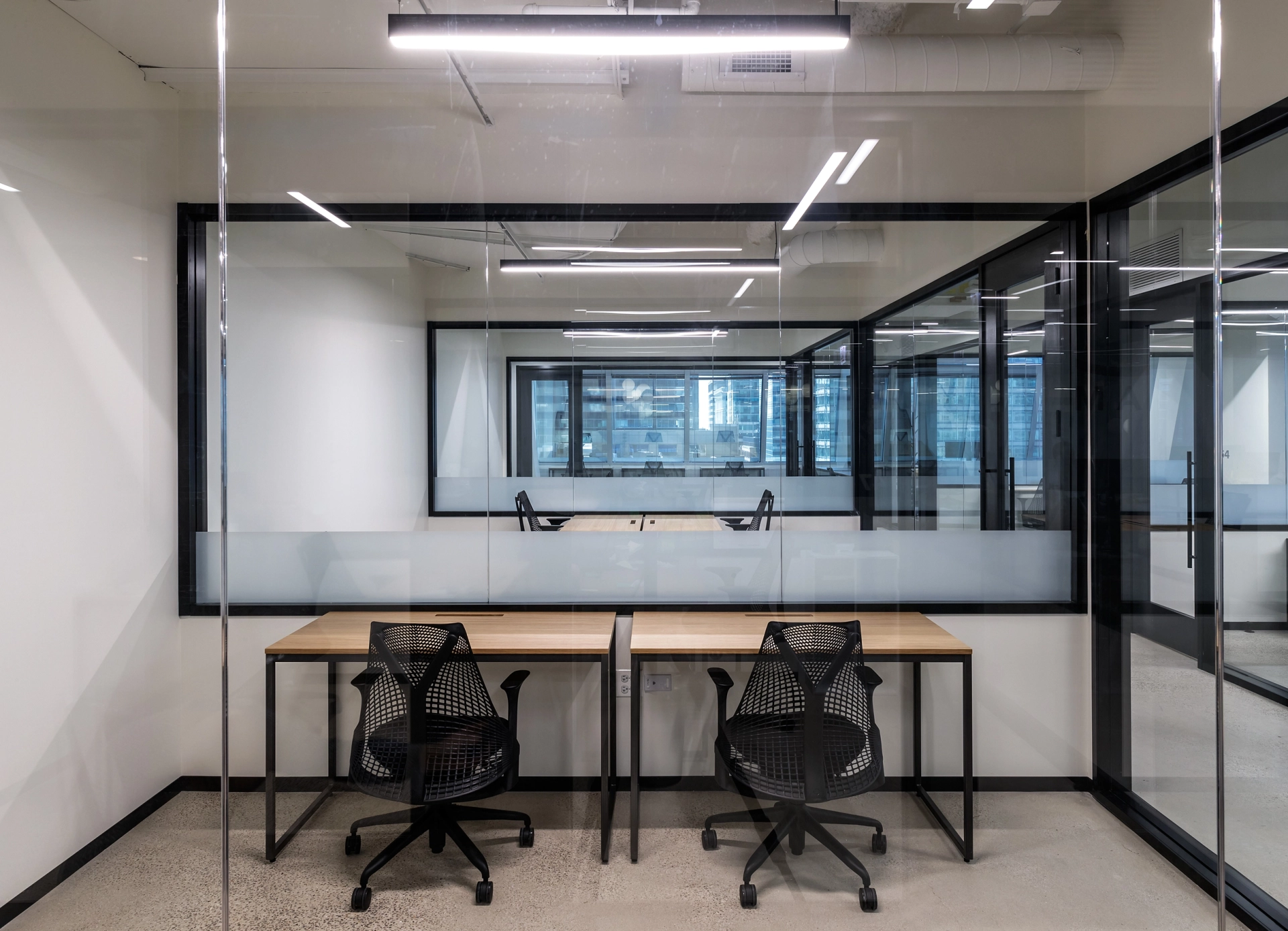 A coworking office in Chicago featuring glass walls, two desks, and chairs.