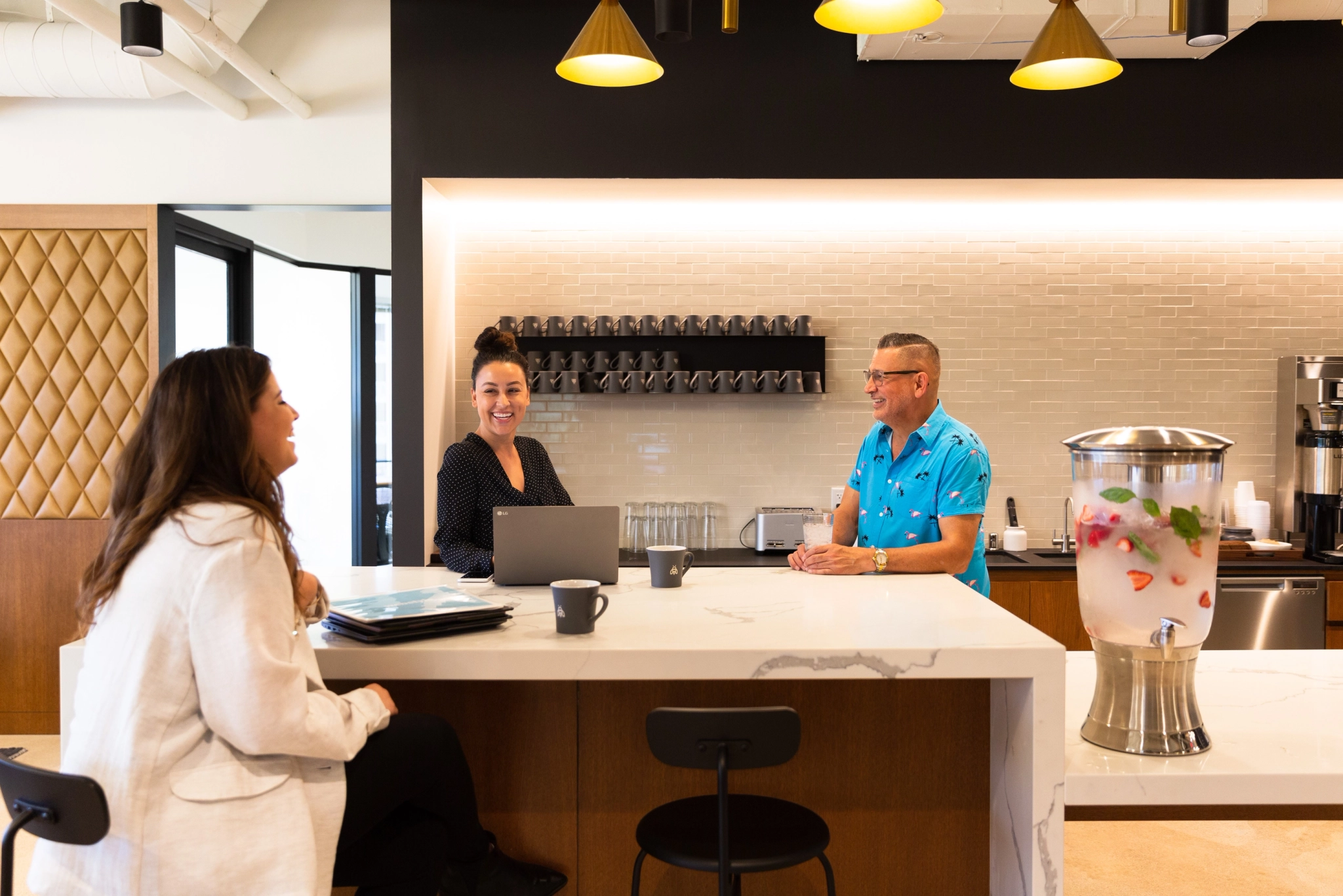 a group of people sitting at a coworking counter in an office workspace.