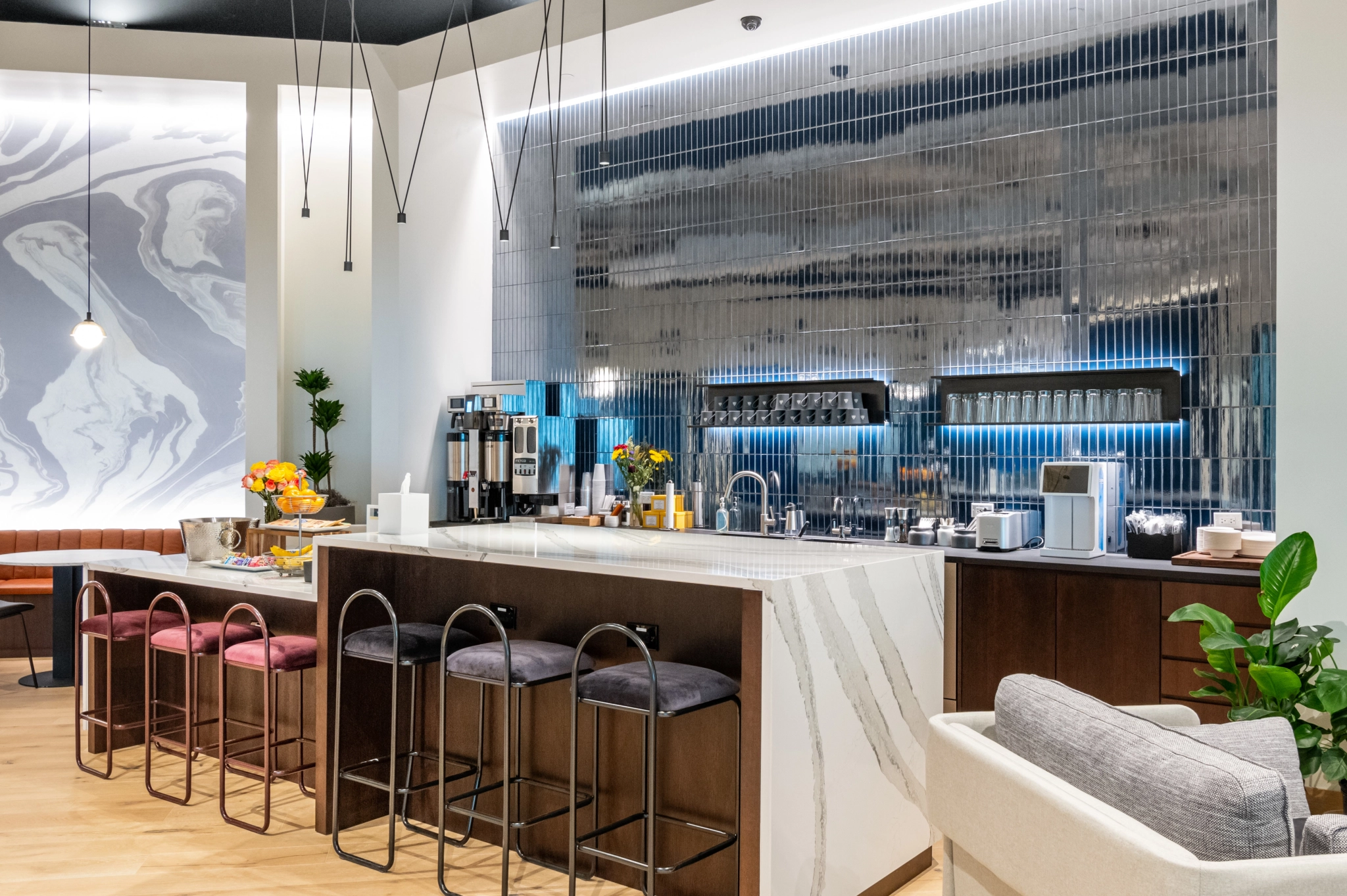 Moderne koffiebar in Tampa met zitplaatsen, marmeren aanrecht, espressomachines en decoratieve wandtegels. Bloemen en diverse artikelen sieren de toonbank. Ideaal als informele werkplek voor creativiteit of informele ontmoetingen.