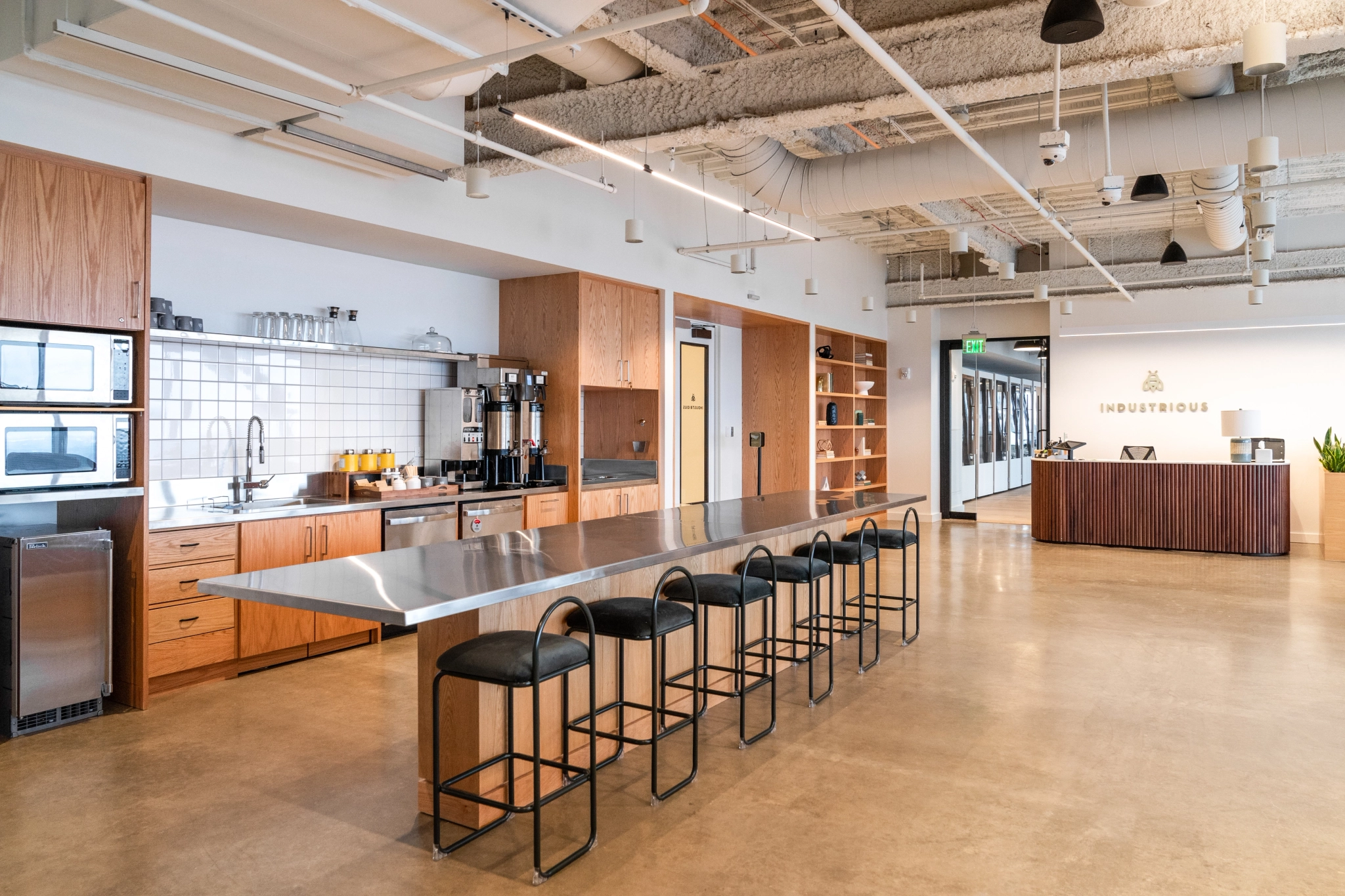 A coworking space with an office and kitchen area featuring bar stools.