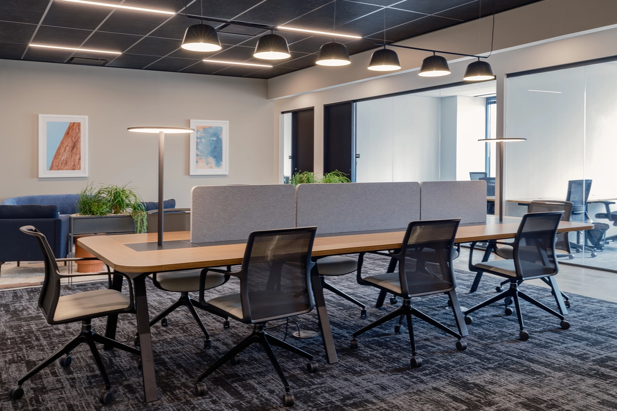 Modern meeting room workspace in Austin with a long table, chairs, and pendant lighting.