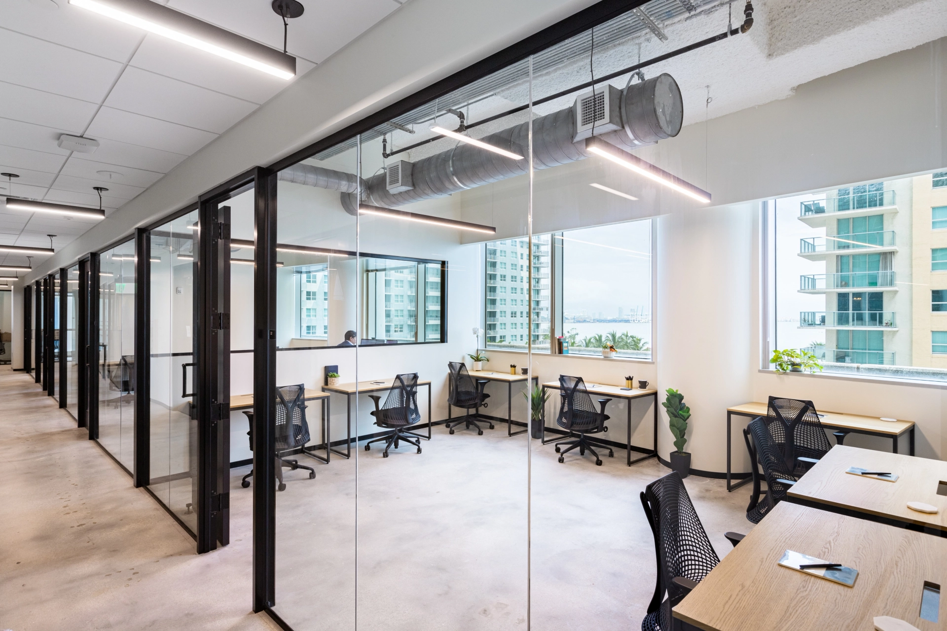 An open Miami workspace with glass walls and desks.