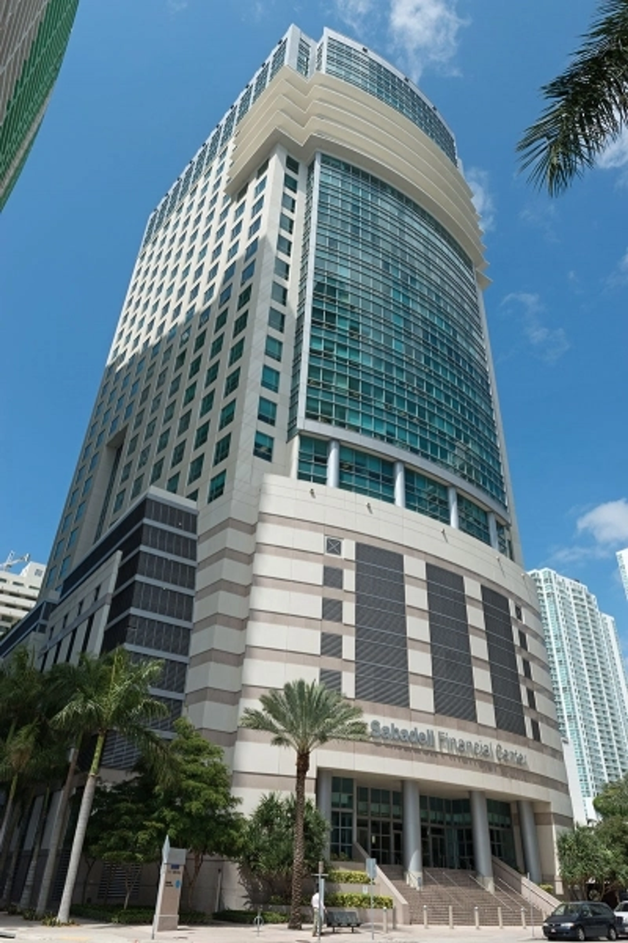 An office building with palm trees in front.