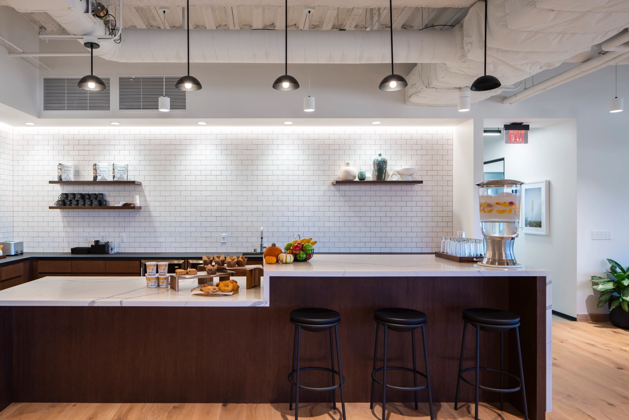 An open coworking space with a kitchenette equipped with stools and a bar.