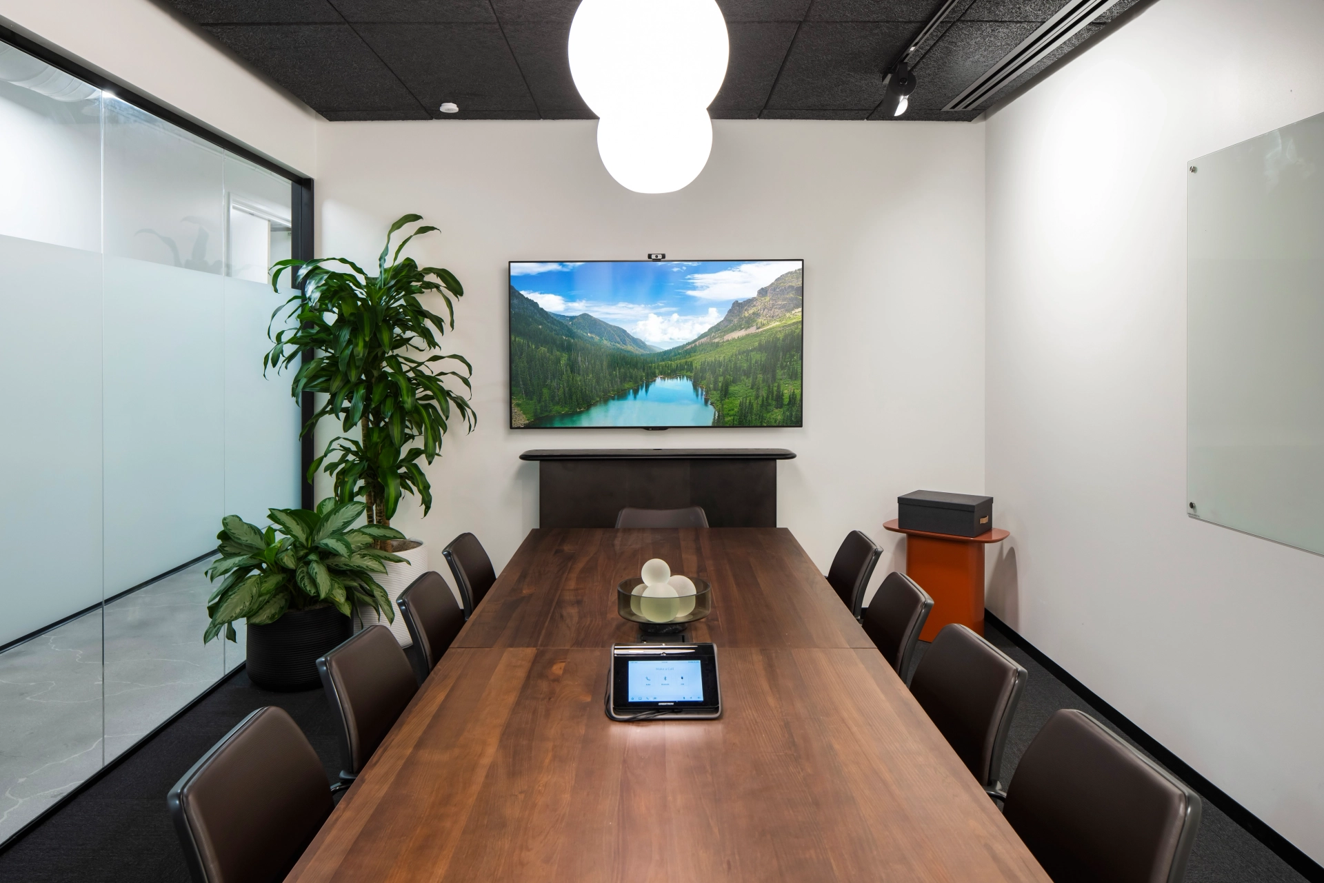 Une salle de réunion dans un bureau ou un espace de coworking avec une télévision au mur.