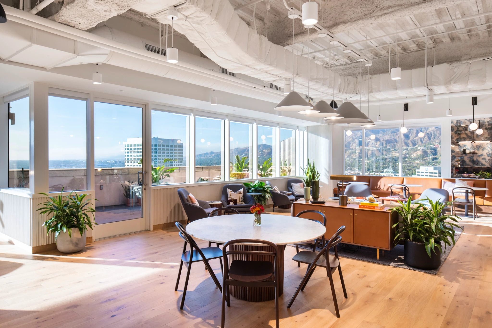 A wooden table and chairs in a coworking office with a view of the mountains.