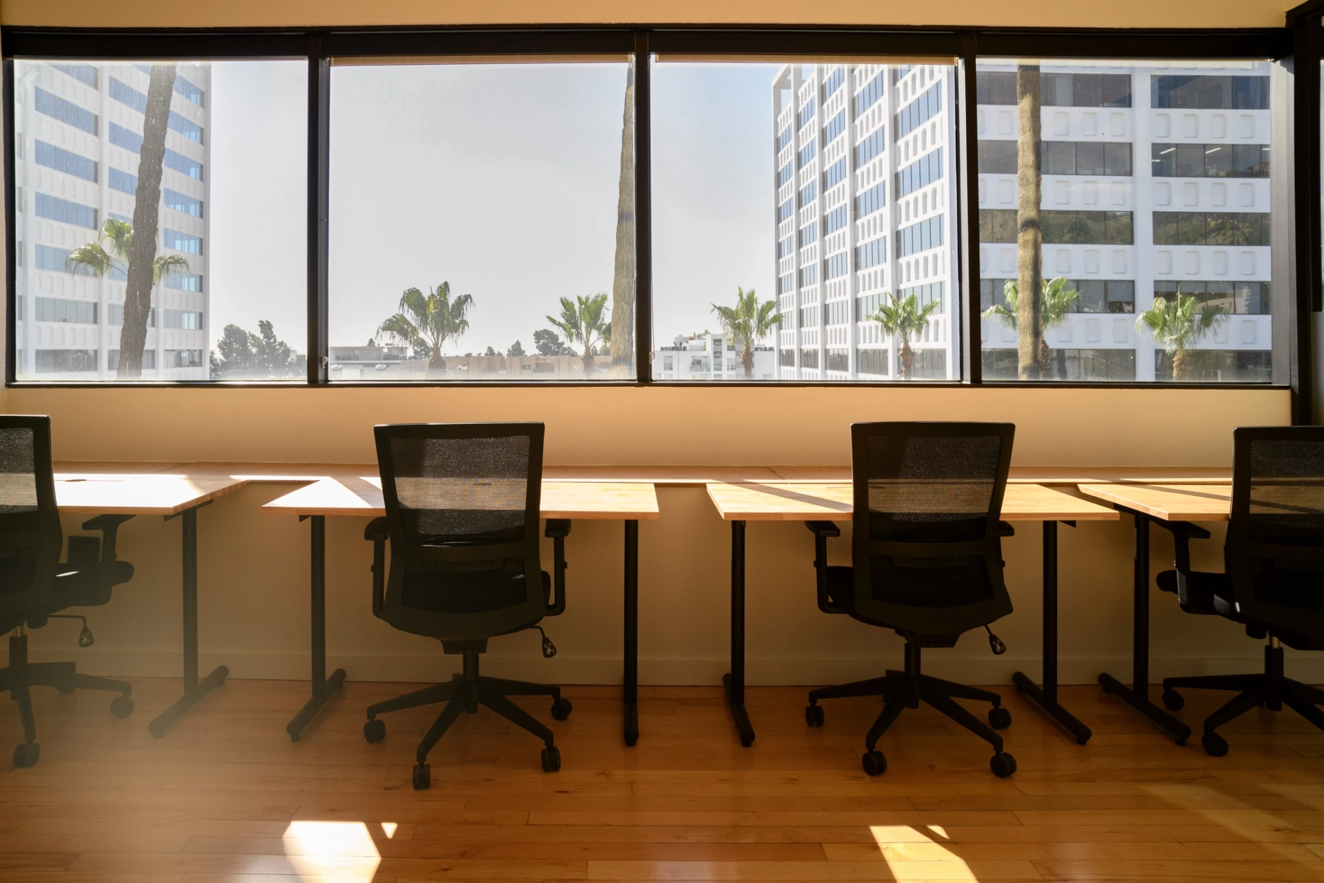 A coworking office with large windows and desks arranged in a row.
