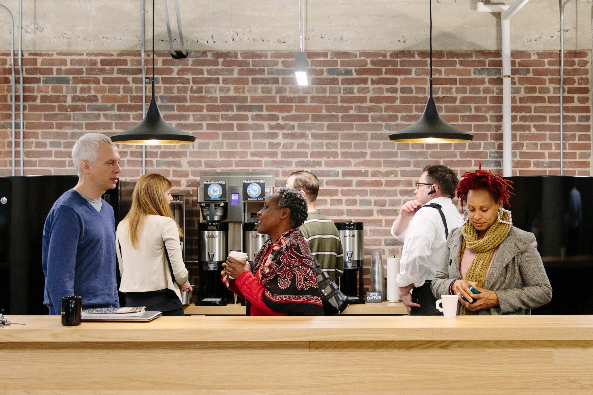 a group of people gathering in a coffee shop workspace.