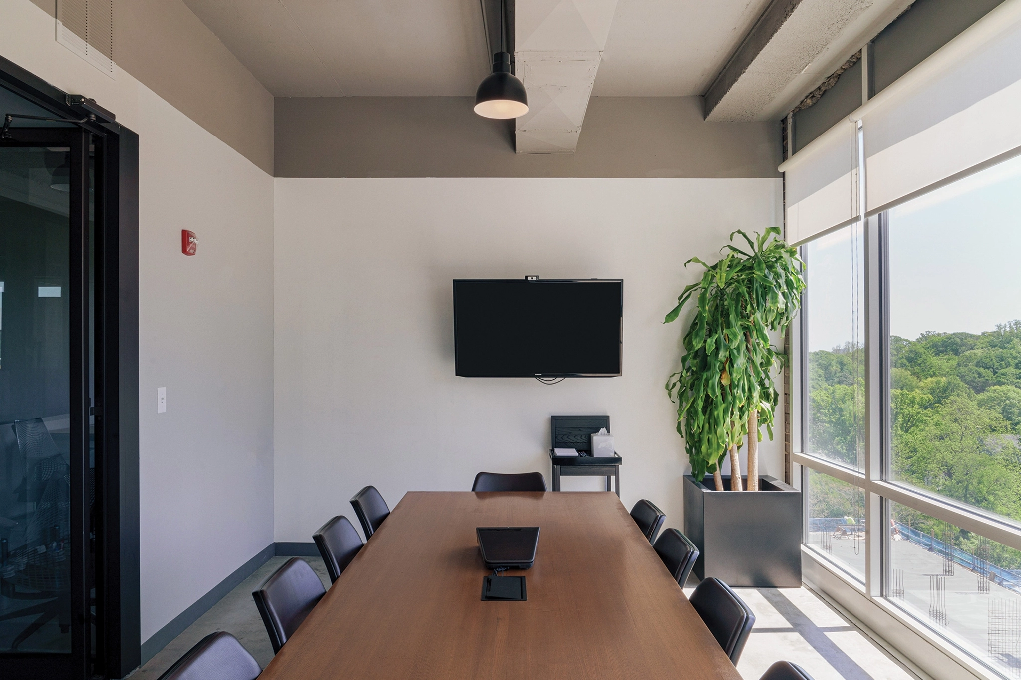 A coworking meeting room equipped with a table, chairs, and a large window.