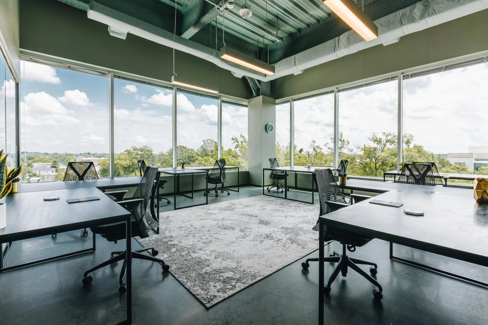 An open coworking space with large windows overlooking a city.