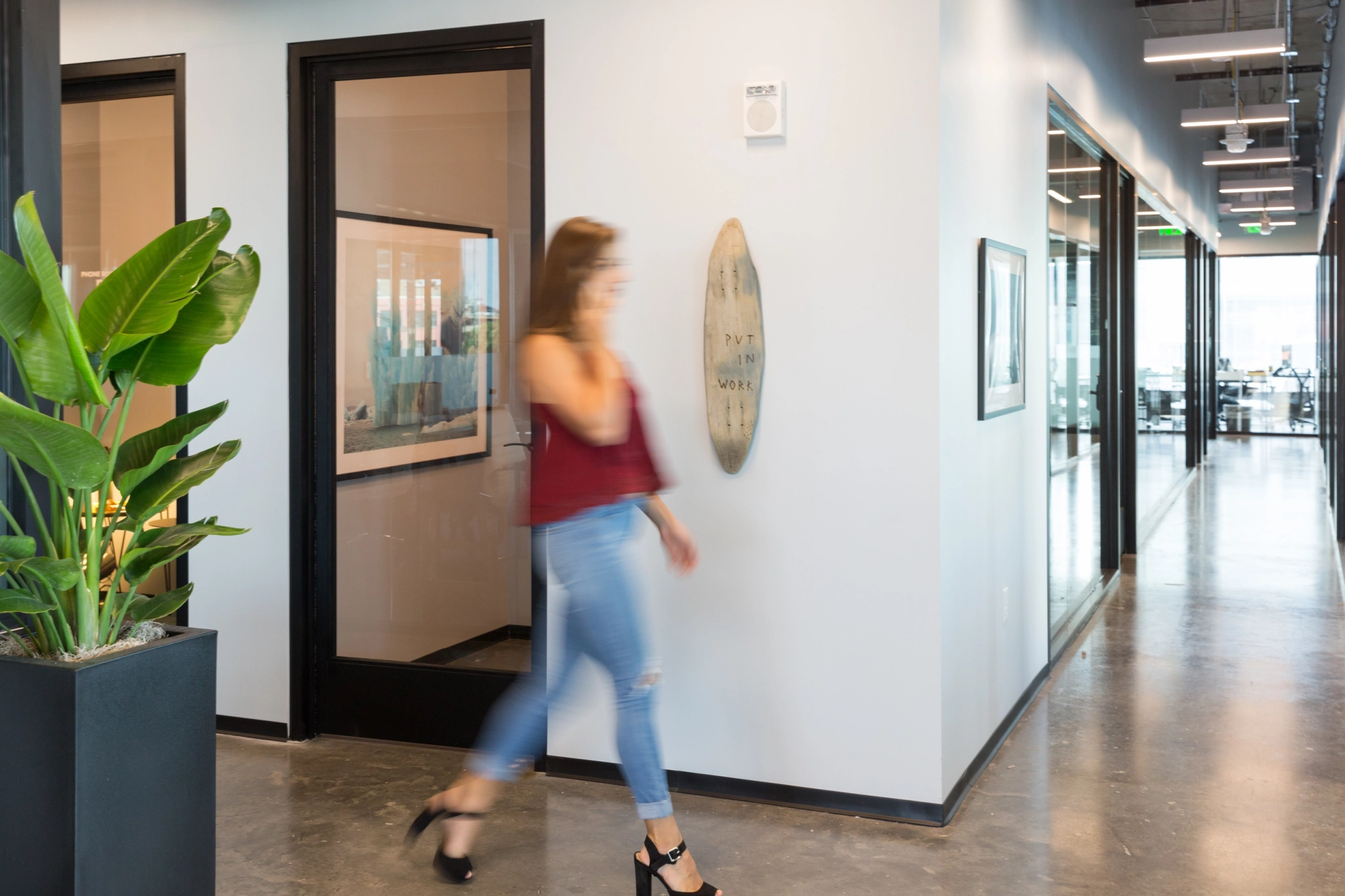 a woman walking down an office hallway.