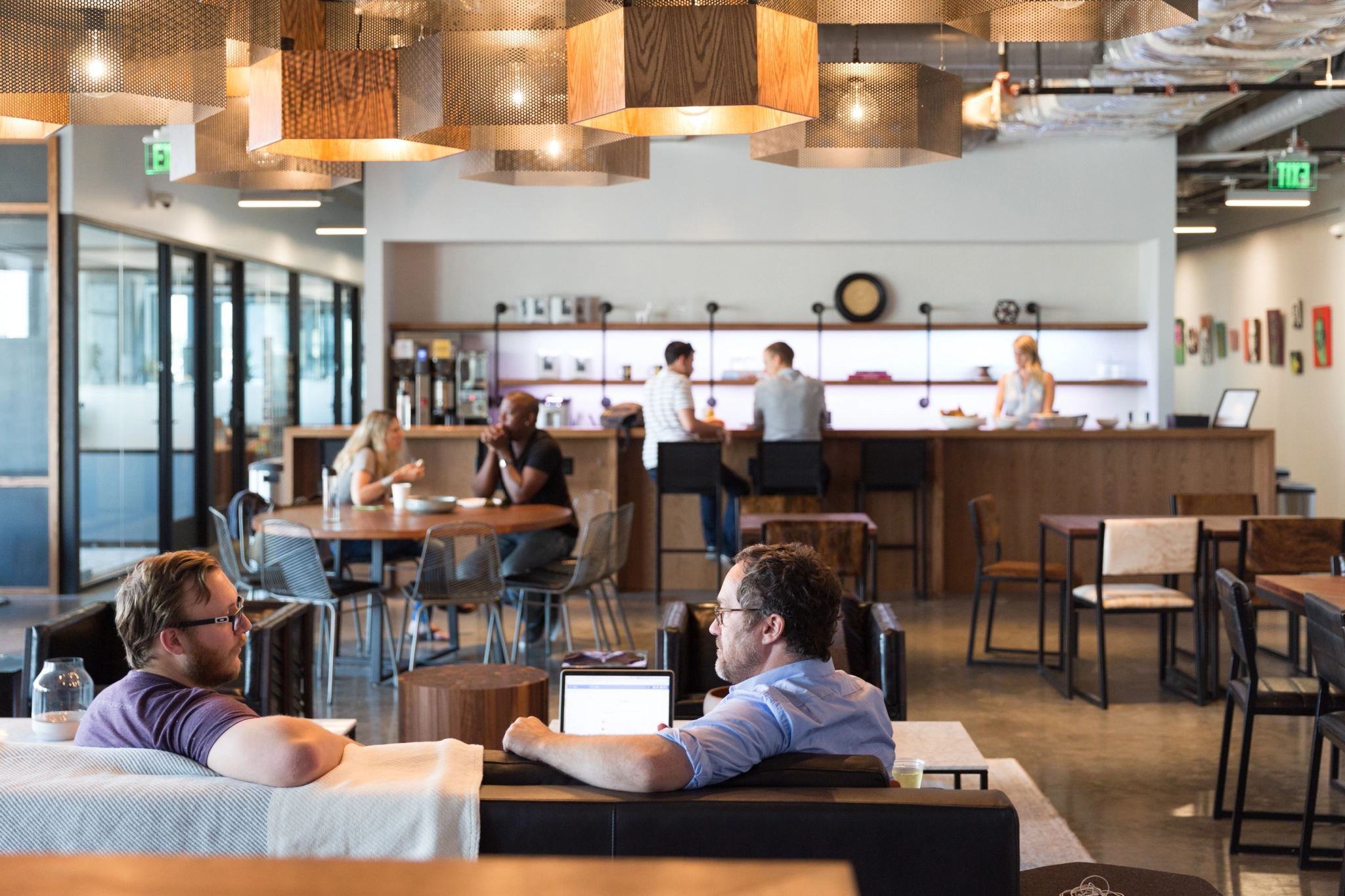 a group of people sitting at tables in a restaurant turned into office workspace or meeting room.