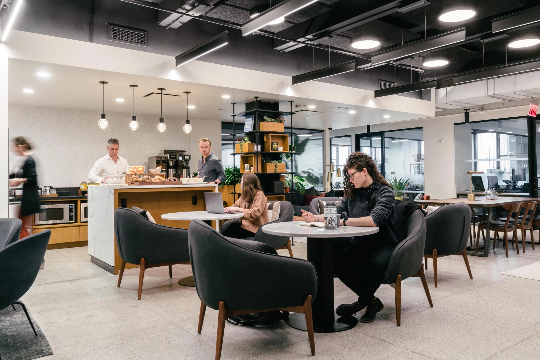 People are sitting at tables in a coworking office space.