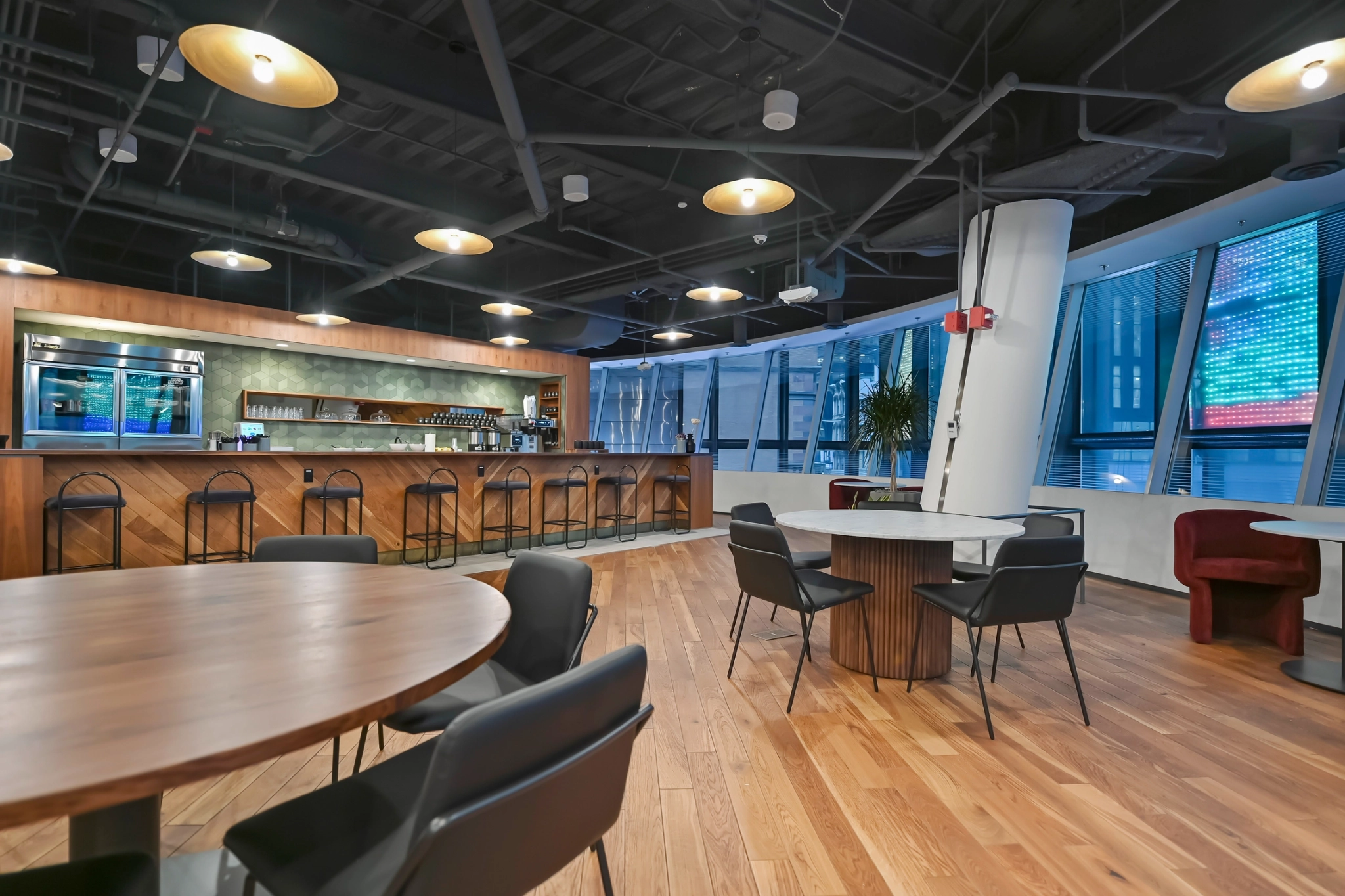 A modern workspace with wooden floors and a bar area.