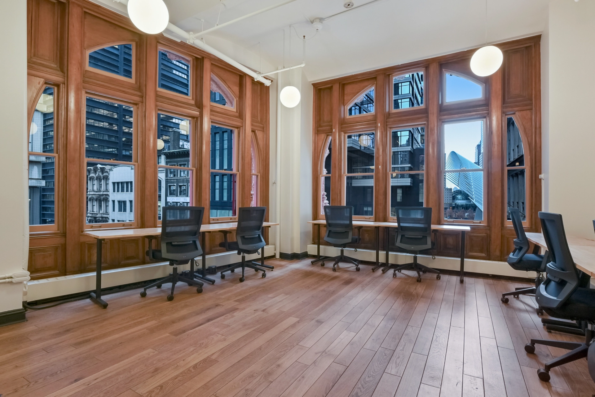 An empty coworking workspace with wooden desks and large windows.