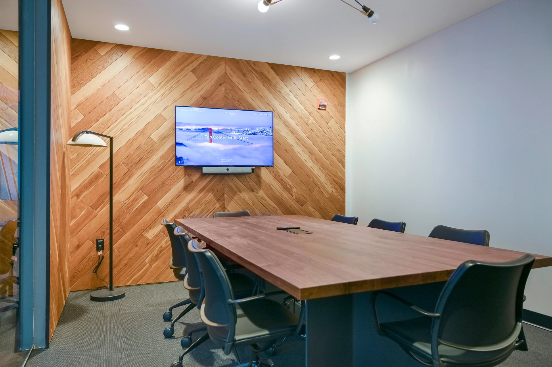 Une salle de réunion de coworking avec des murs en bois et une télévision.