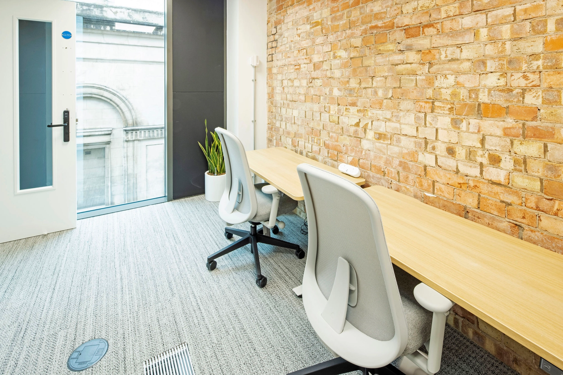 Un espace de coworking avec des bureaux, des chaises et un mur de briques.