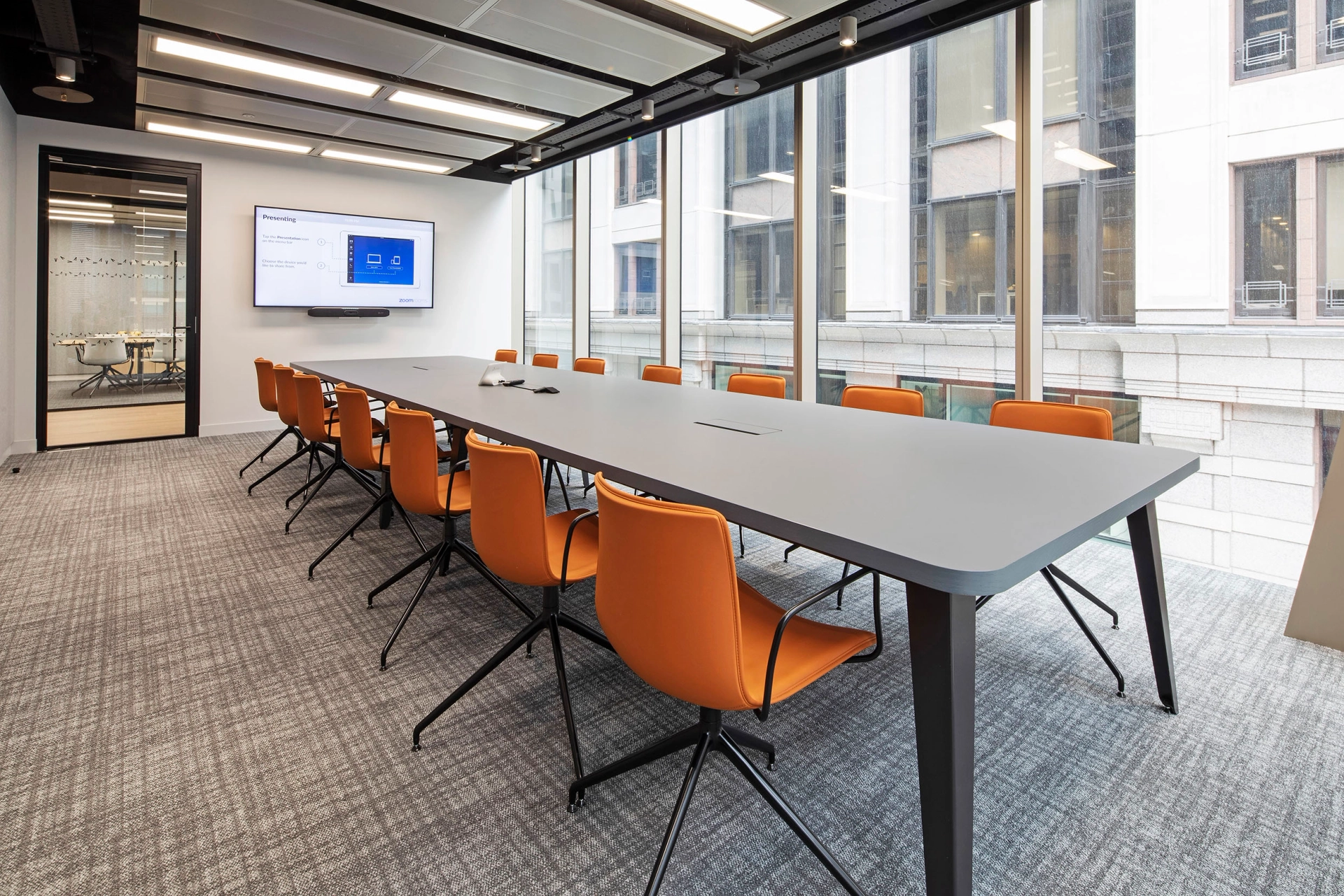 Une salle de conférence de coworking à Londres avec une grande table et des chaises orange.