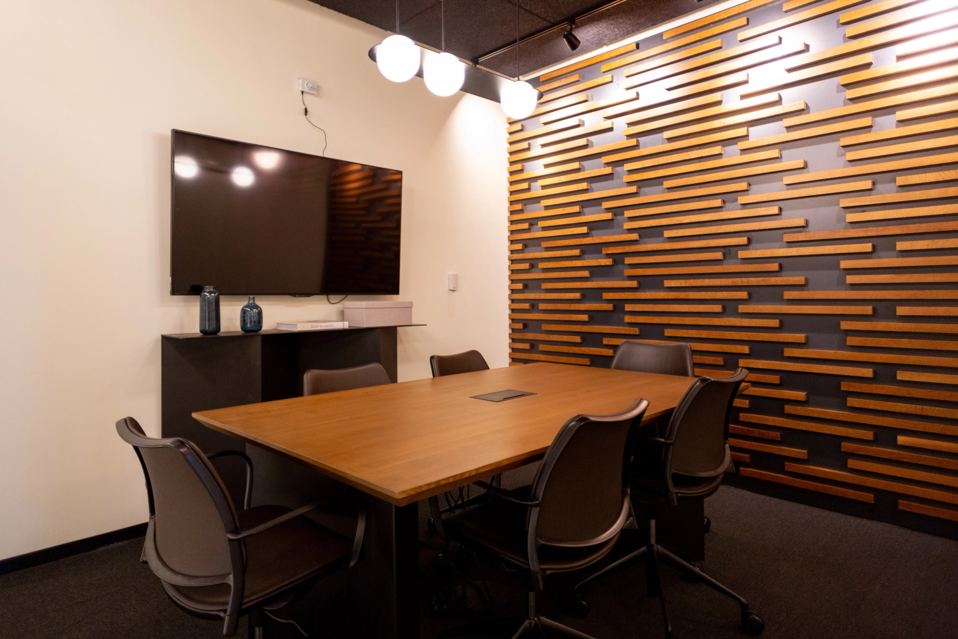 A coworking office space offering a meeting room with wooden wall and chairs.