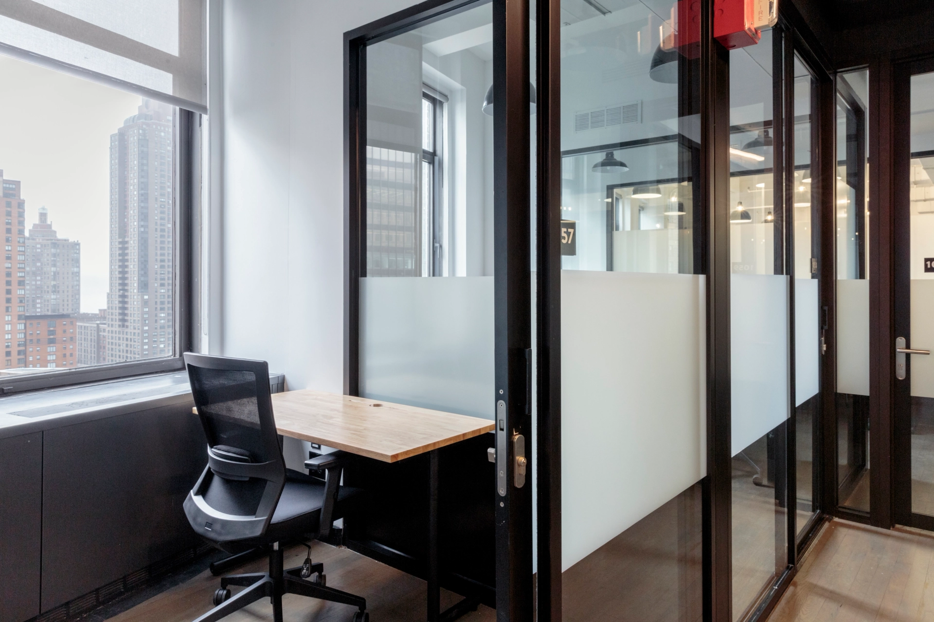 Un espace de travail new-yorkais avec des parois vitrées et un bureau.