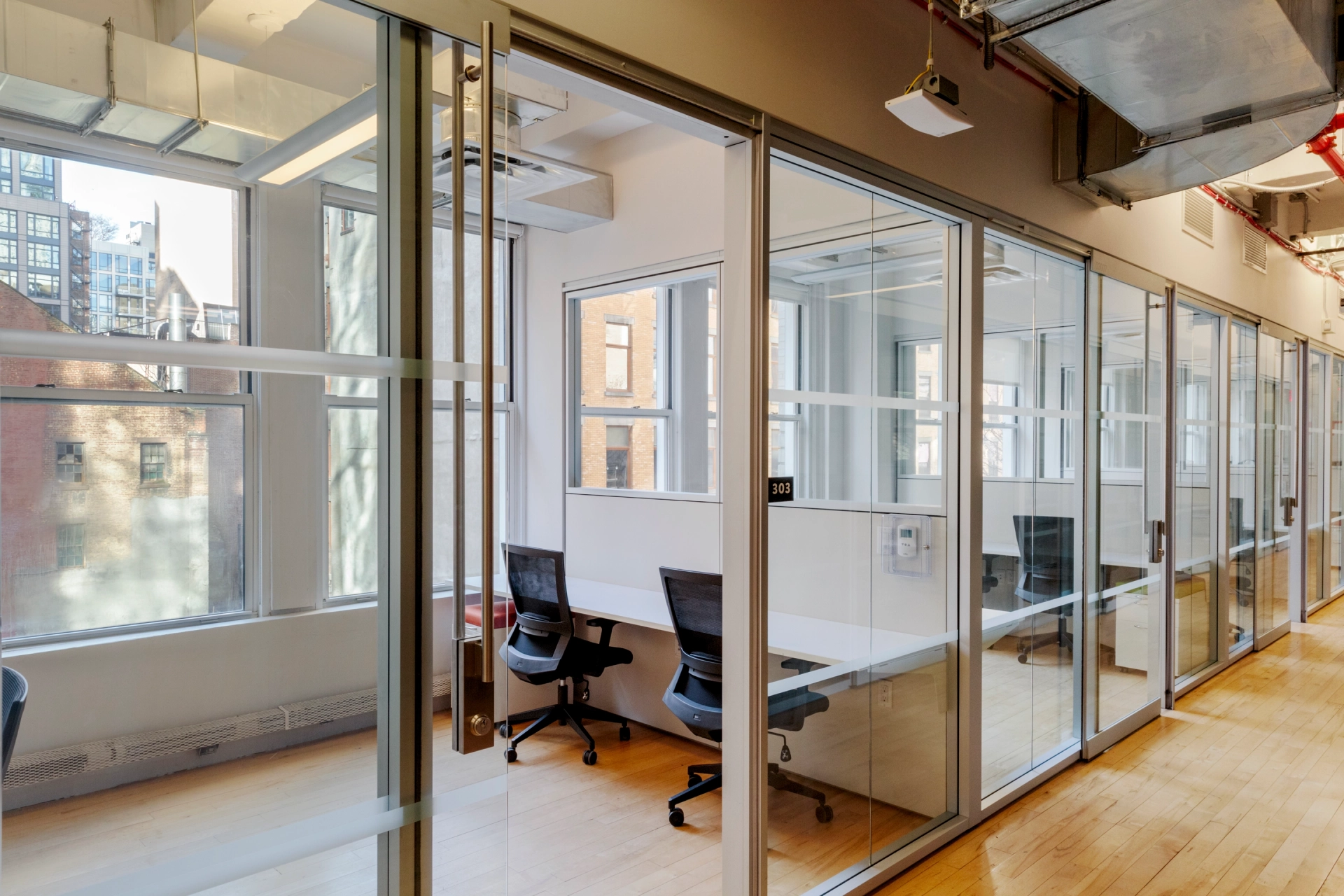 A New York coworking space featuring glass walls and a desk.