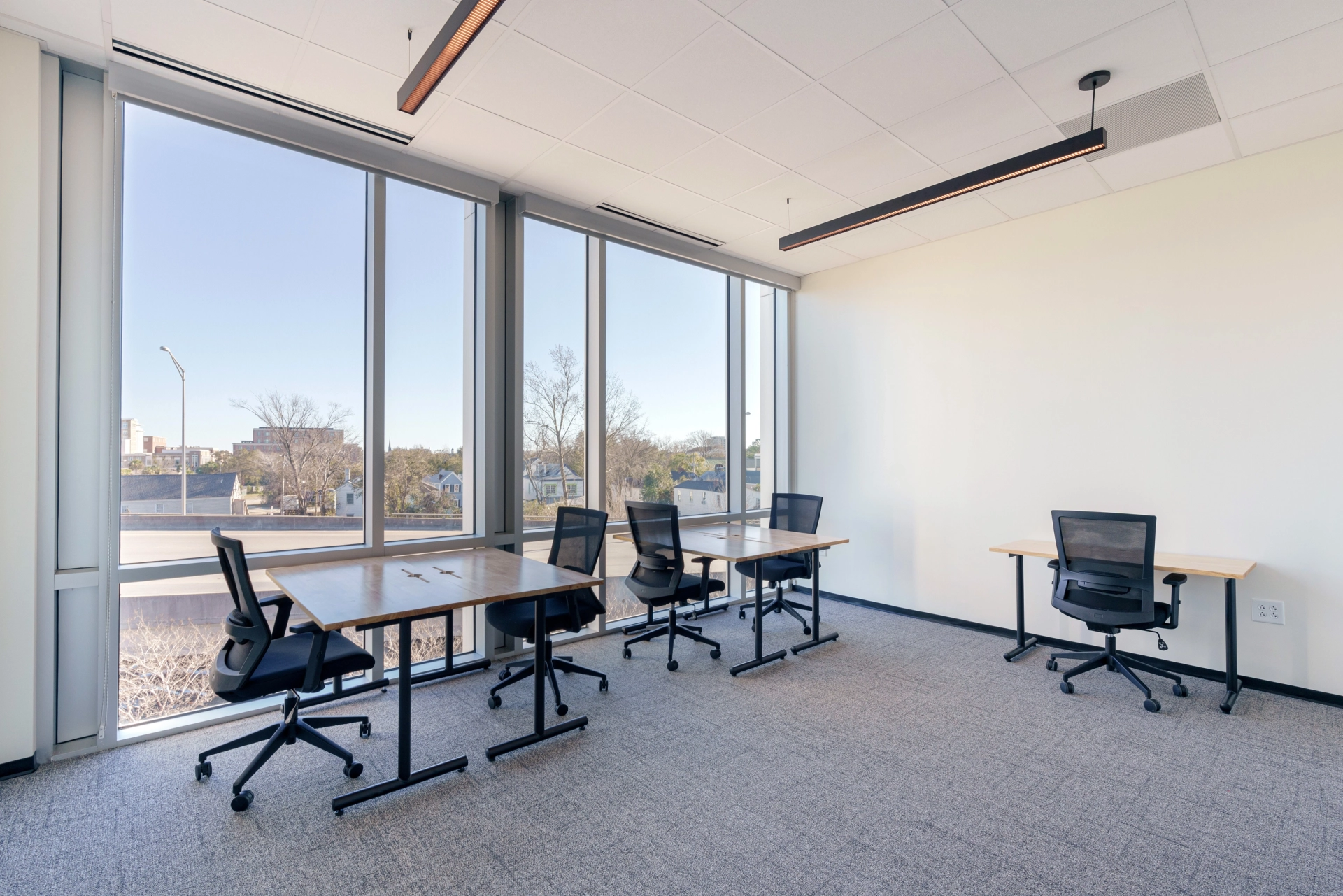 Un espace de travail de coworking équipé de bureaux, de chaises et de grandes fenêtres.