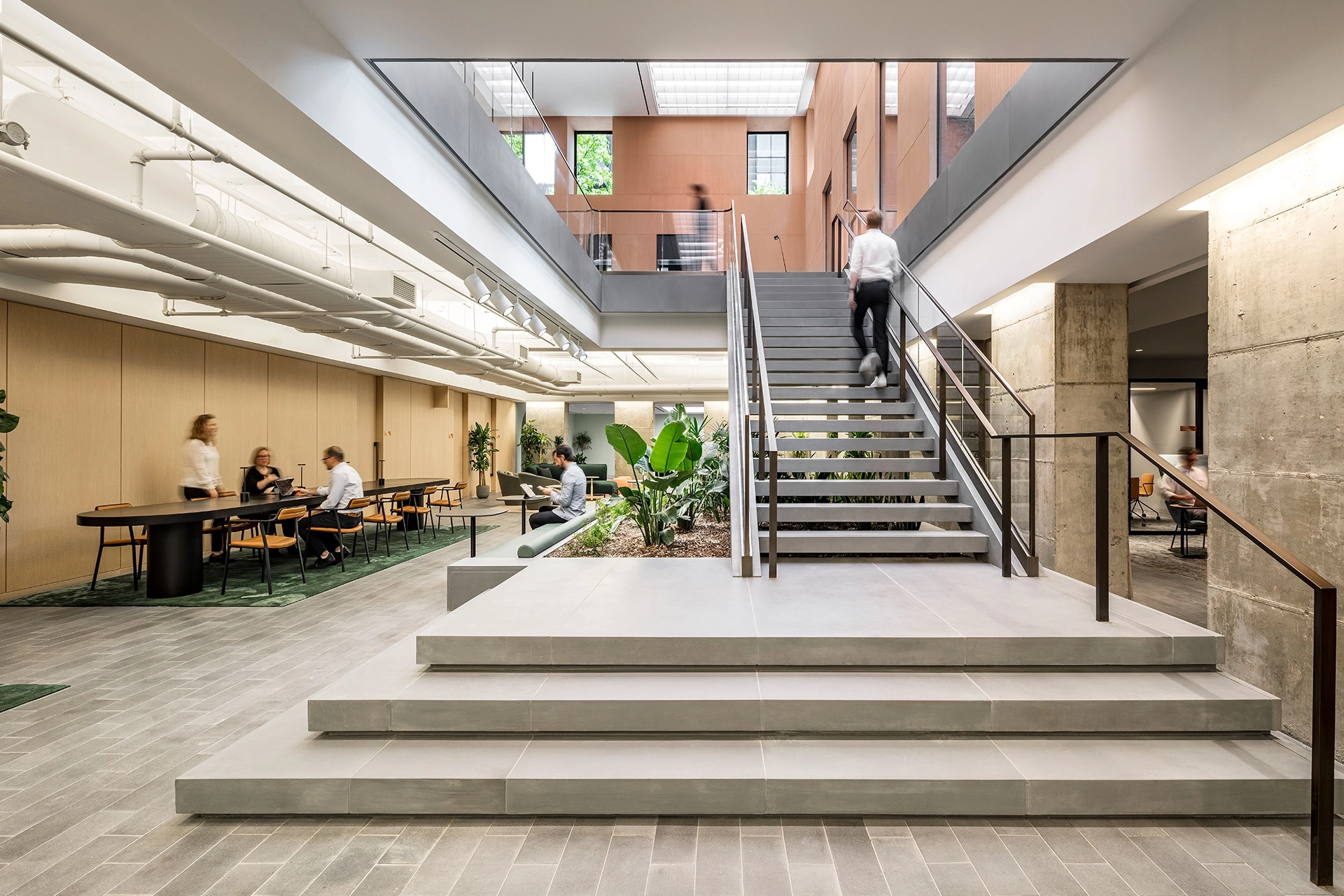 Un espace de travail de coworking à New York avec des escaliers et des plantes comme éléments de conception centraux.