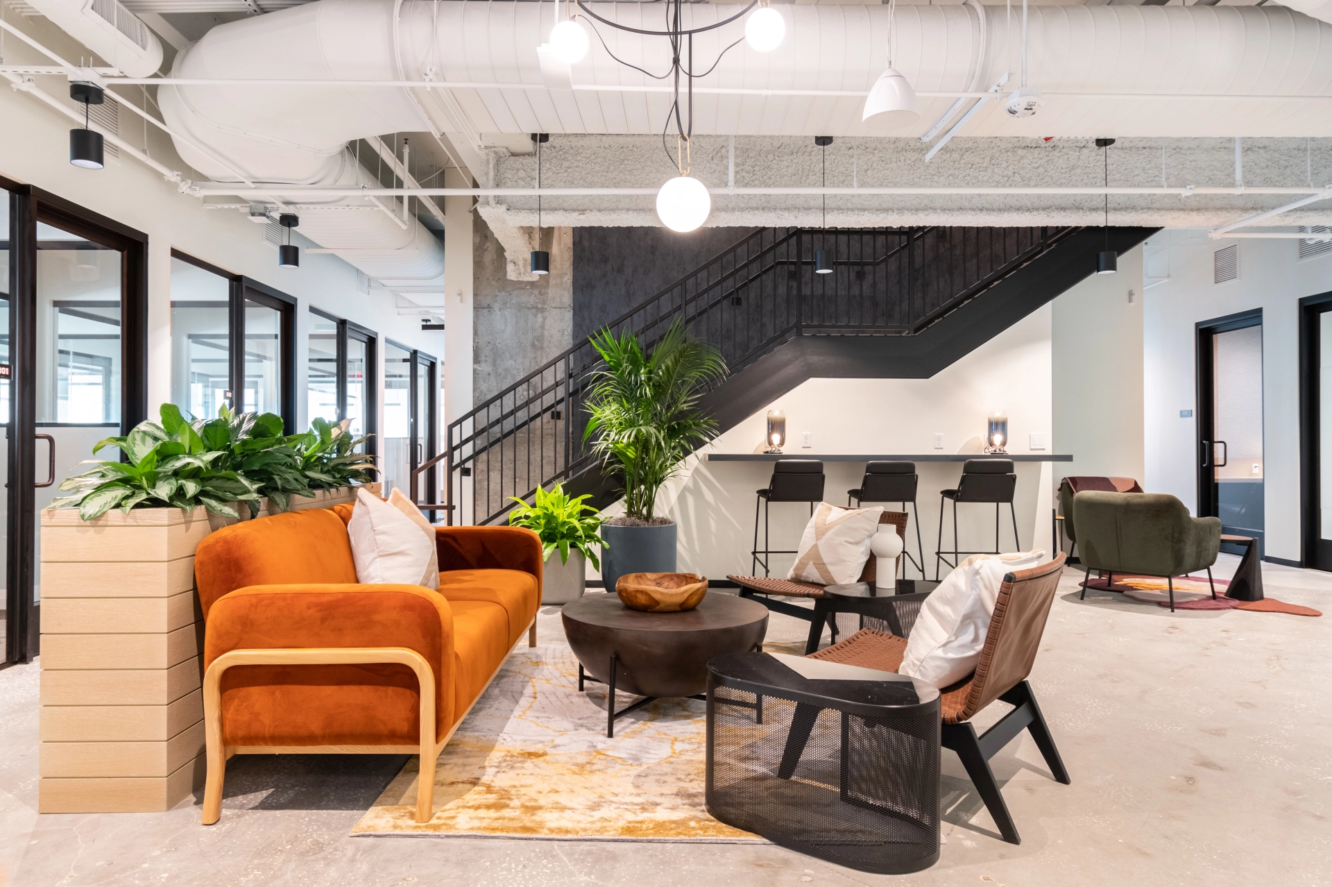 Un espace de coworking à Saint-Pétersbourg avec un bureau moderne au mobilier orange et un escalier, équipé de salles de réunion.