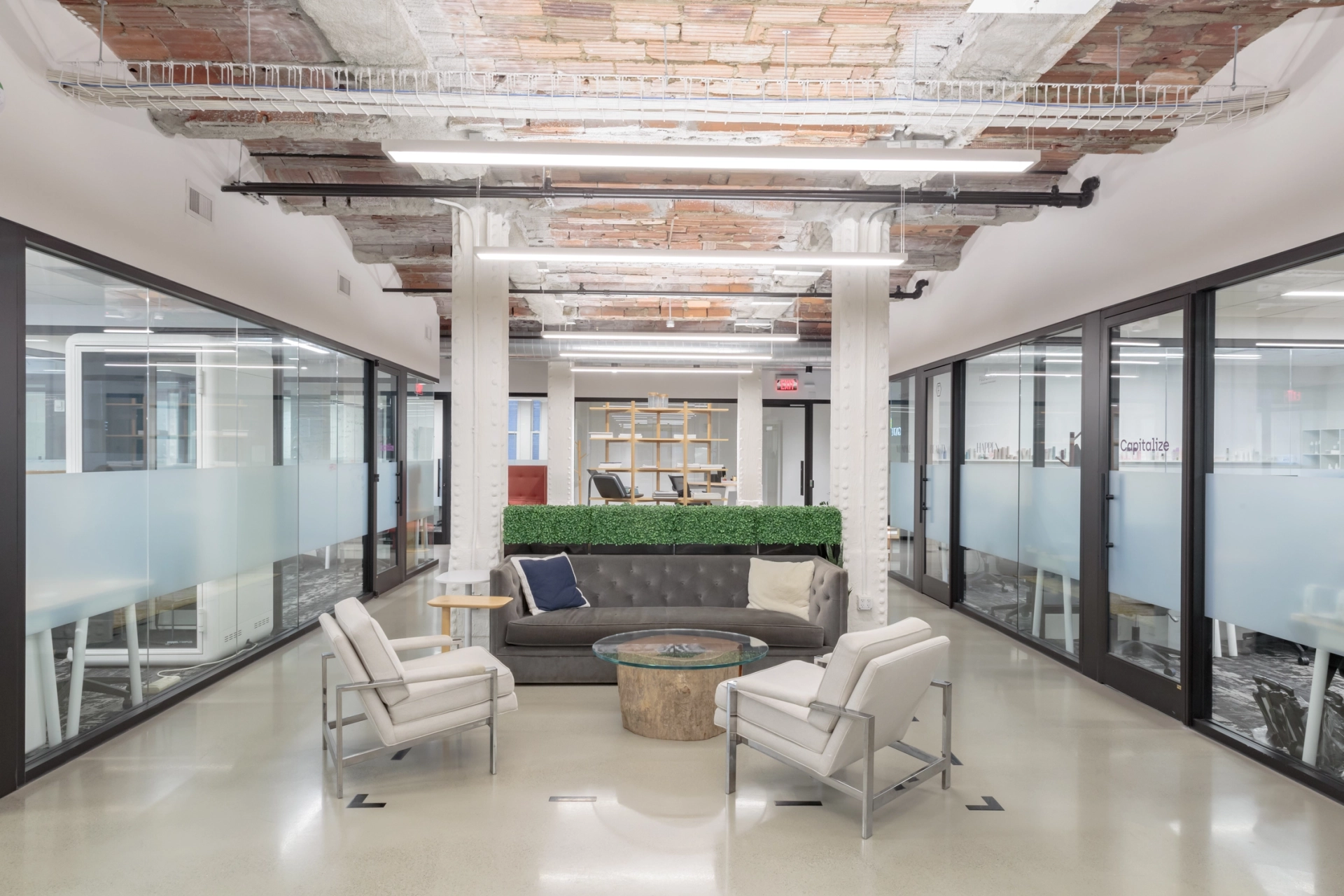 Un espace de coworking à New York avec un design d'espace de travail moderne avec des murs en verre et des chaises confortables.