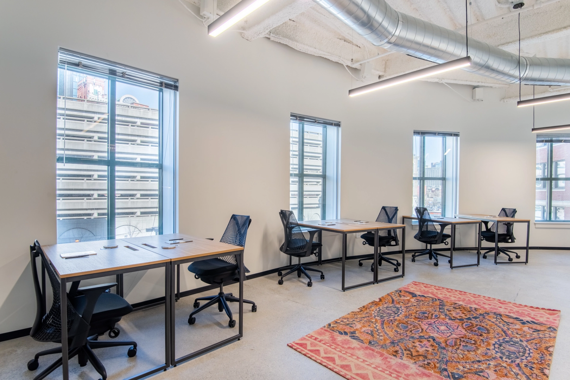 Un espace de coworking avec des bureaux élégants, des chaises ergonomiques et de grandes fenêtres.