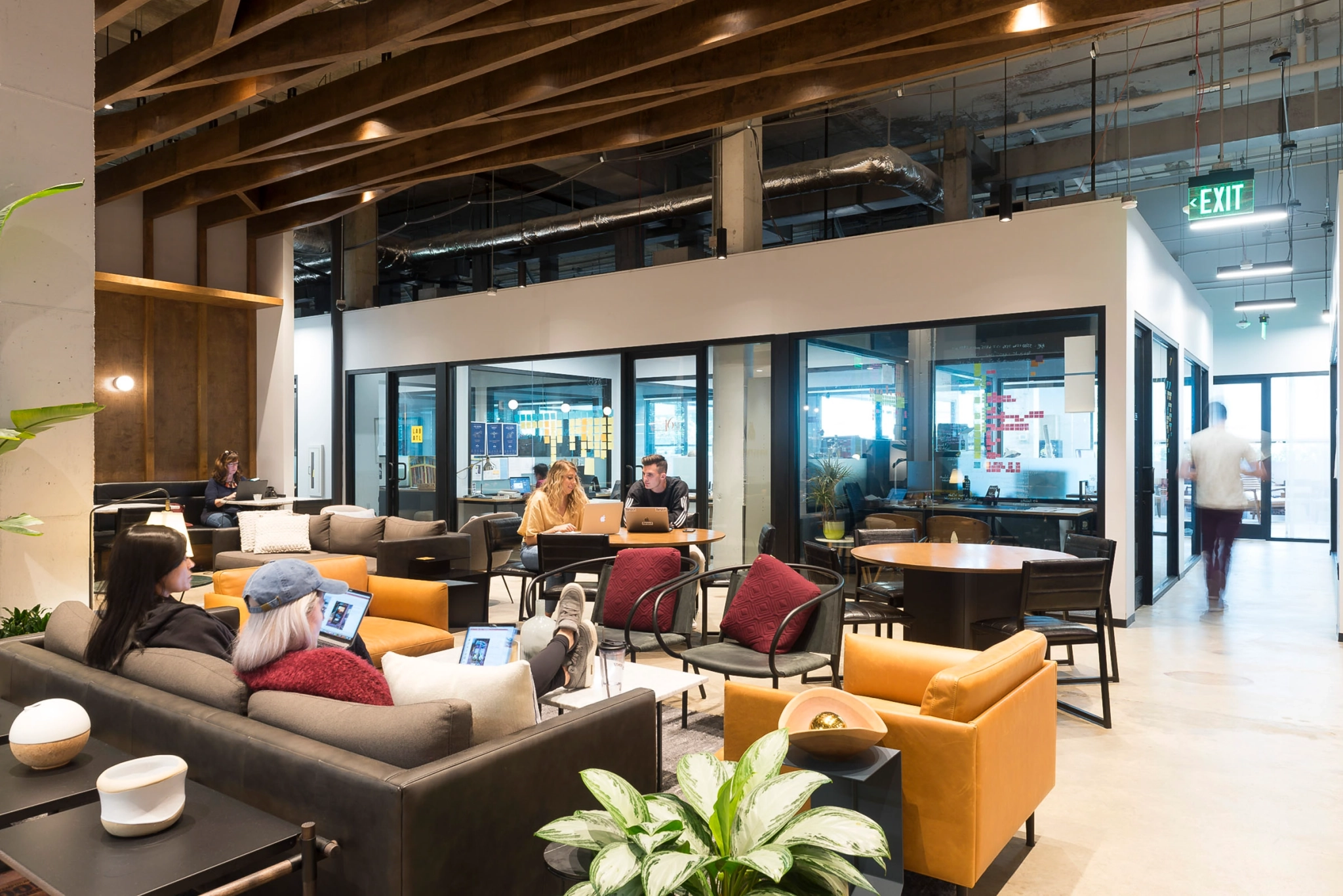 A workspace in an office building where individuals congregate, sitting in chairs.