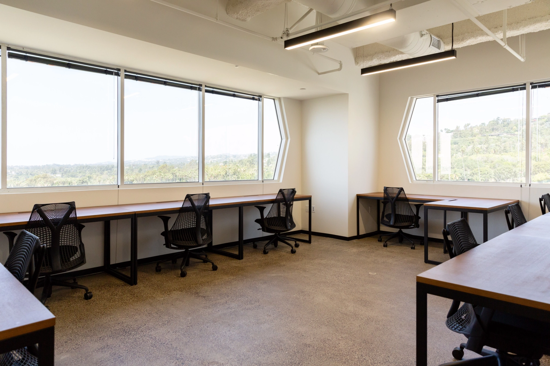 Een ruim coworking-kantoor in West Hollywood, met verschillende bureaus en grote ramen, perfect voor samenwerkingsvergaderingen.