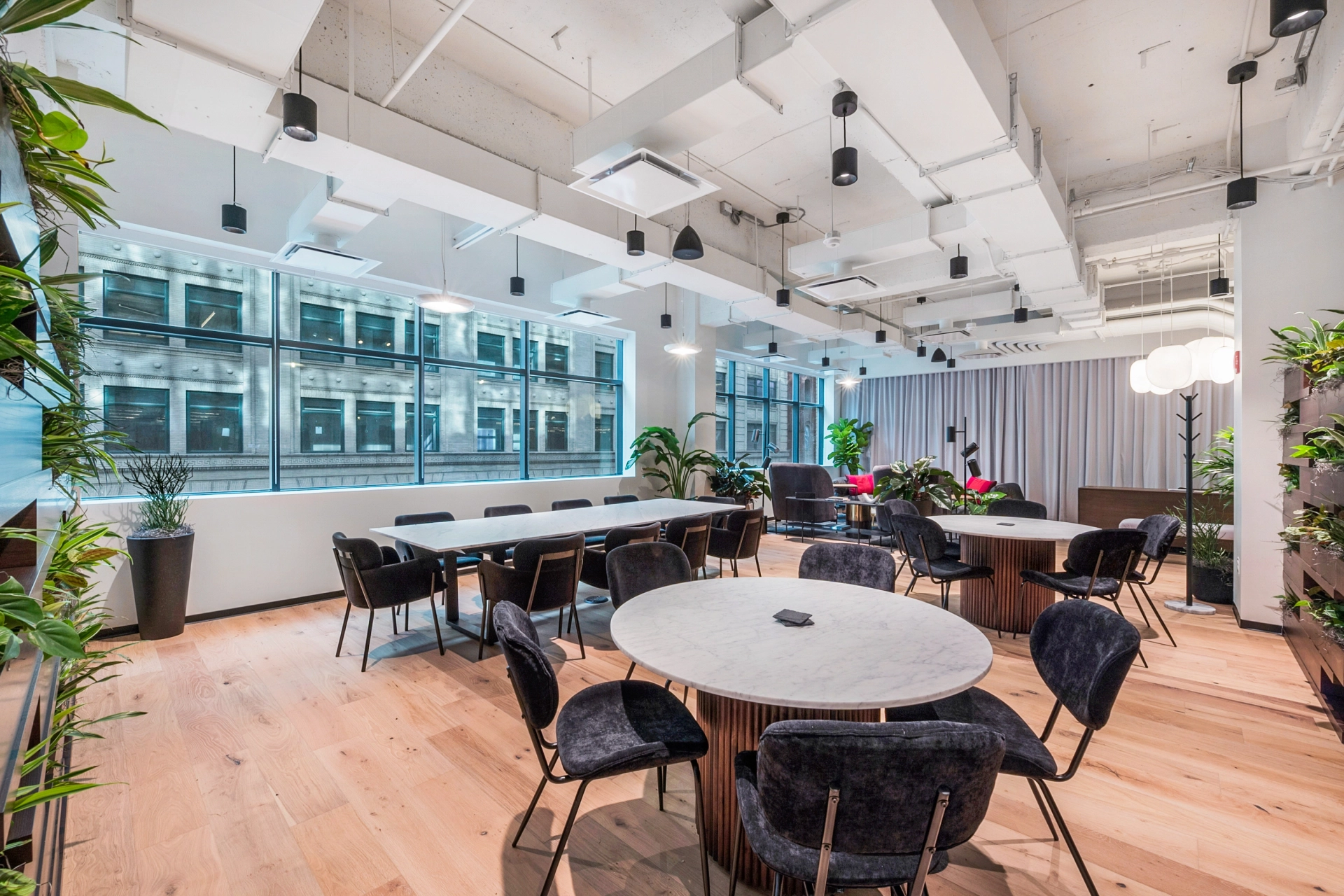 A coworking space featuring a meeting room equipped with a table, chairs, and plants.