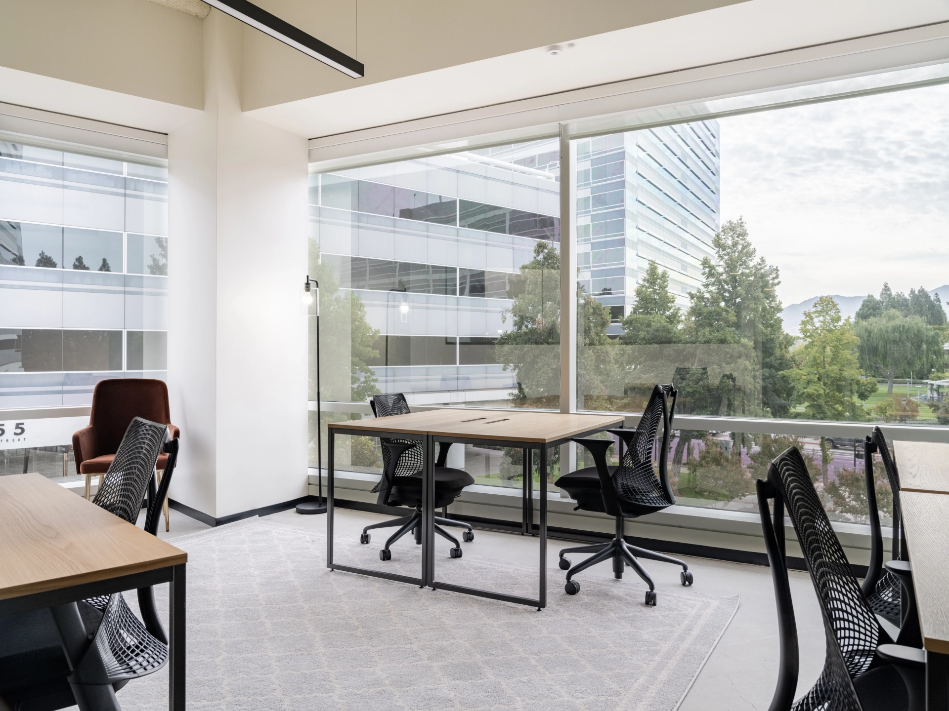 un bureau de coworking avec des bureaux, des chaises et de grandes fenêtres.