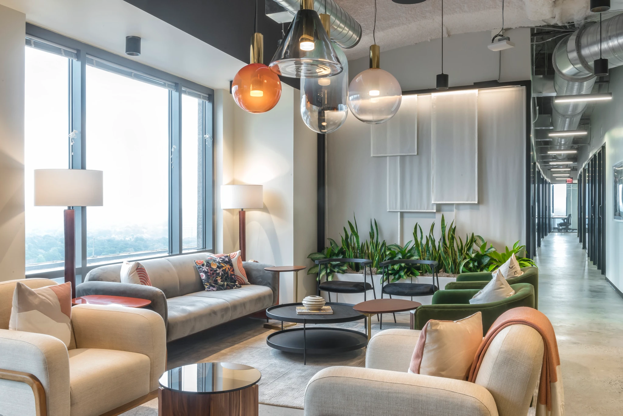 A modern workspace with couches, lamps, and a large window.