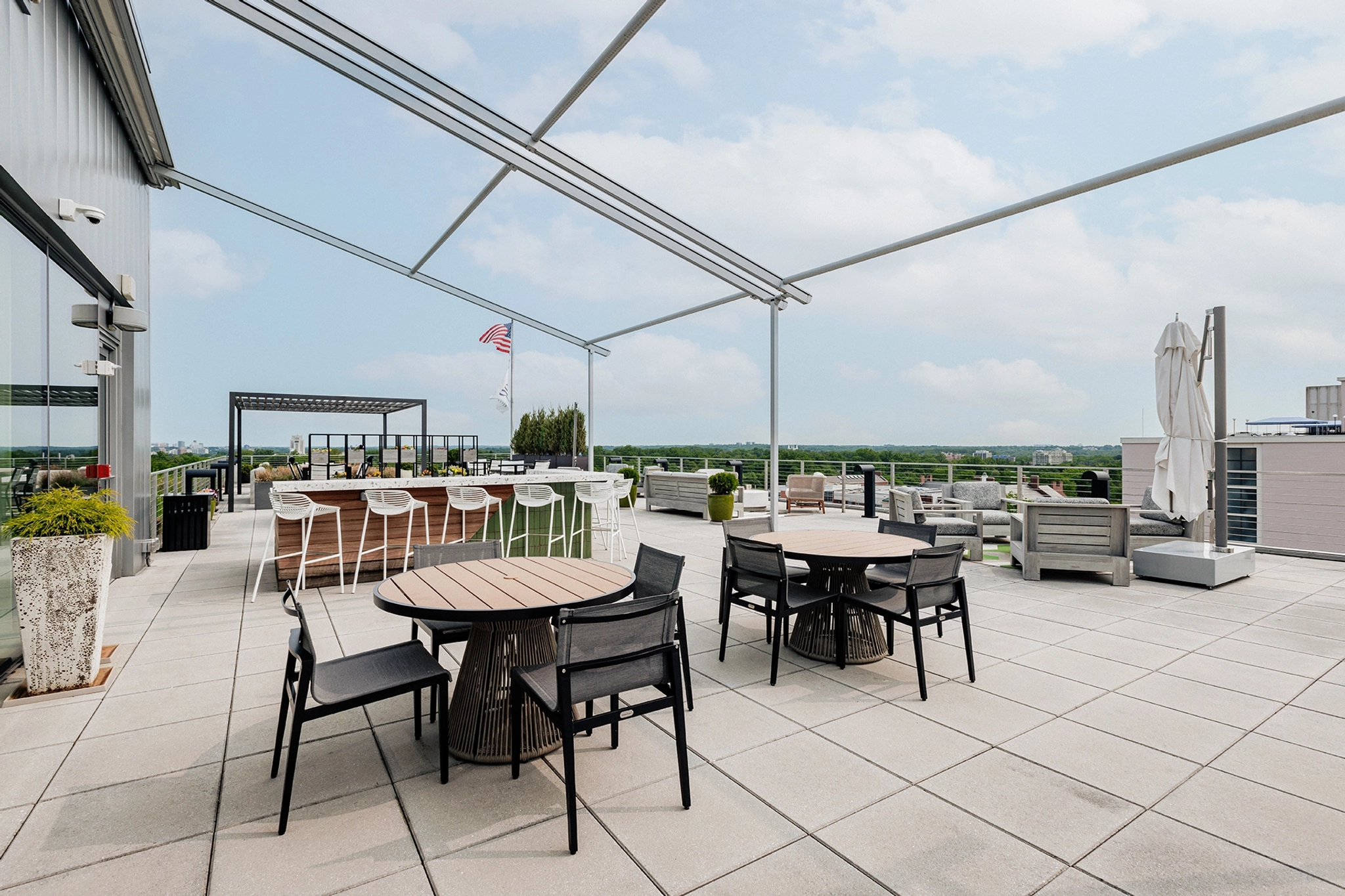 A workspace with tables and chairs on a rooftop patio overlooking the city.