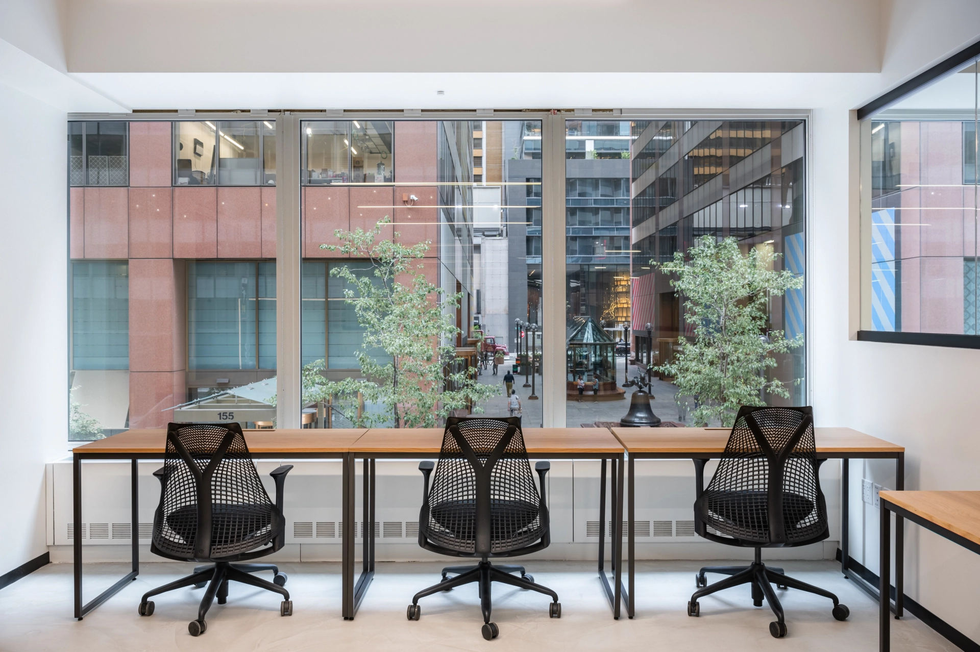 Moderne coworking-kantoorruimte met vrij zicht op New York en drie stoelen rond een gemeenschappelijke werktafel.