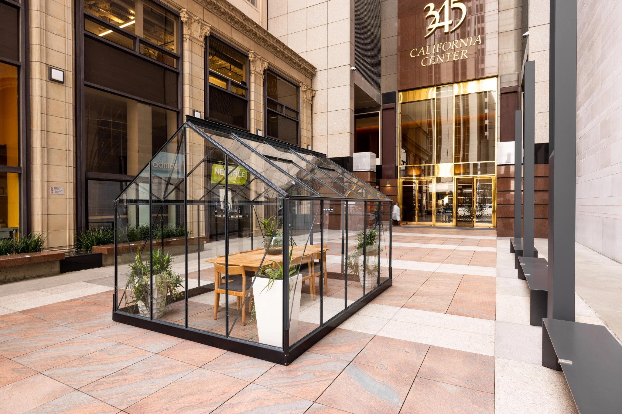 A glass coworking space sits on a sidewalk in front of a building.