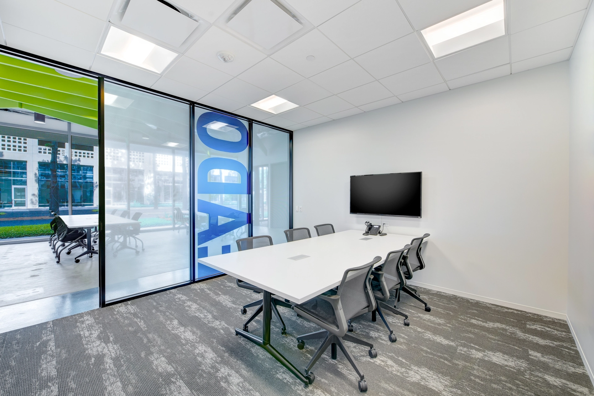 An office meeting room with glass walls and chairs.