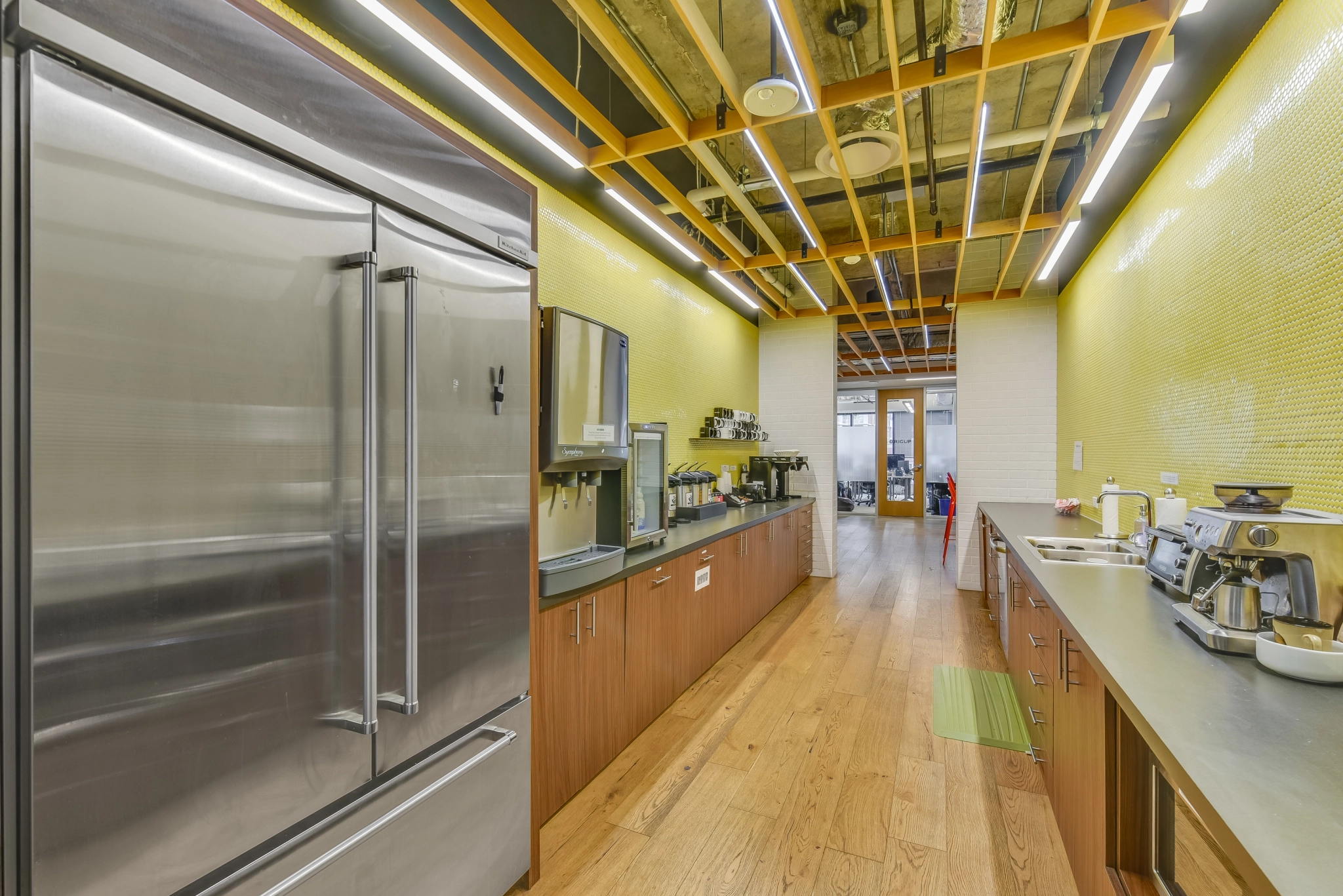 A kitchen in an office in Austin with stainless steel appliances and yellow walls.