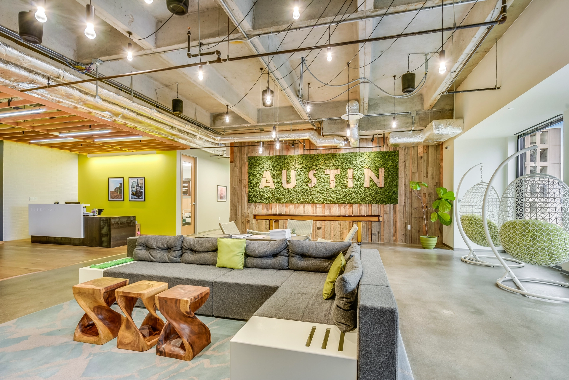 A modern coworking space with a green wall and a green couch.