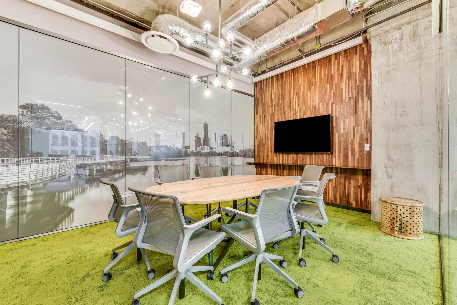 A coworking conference room in Austin with a green carpet and TV.